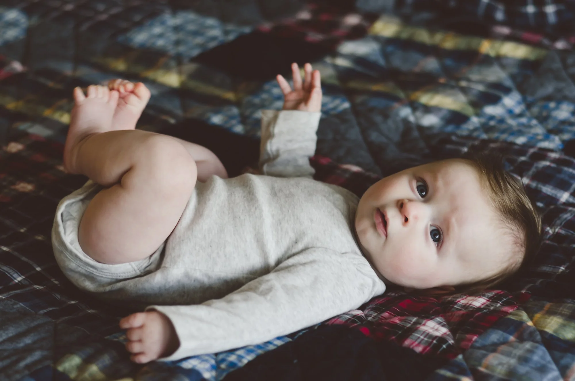 baby boy in gray onesie lays on blue and red plaid blanket, moody, photographer, milestone photographer, clarksville tn, nashville tn, newborn photographer, family photographer, affordable