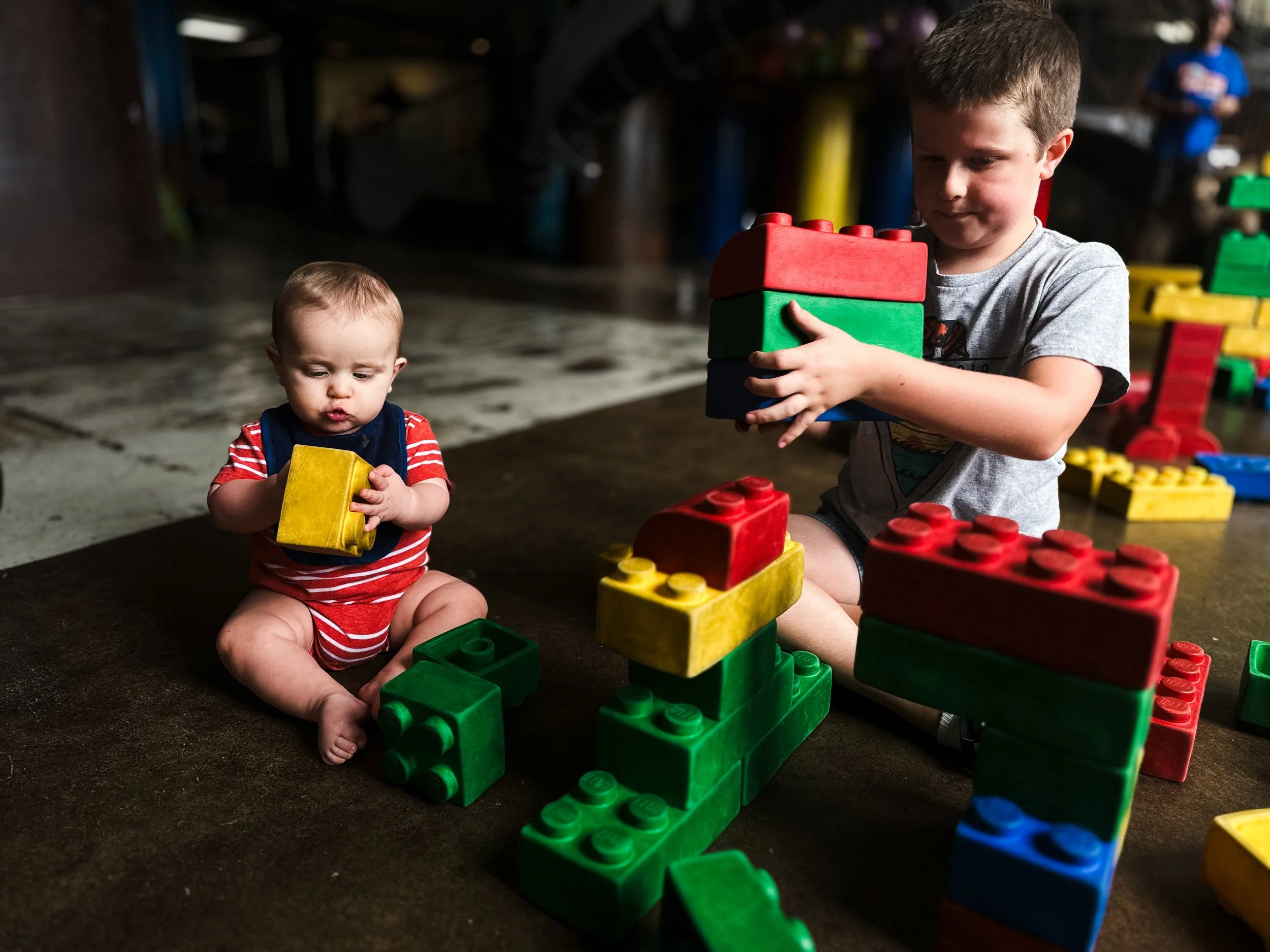 One baby boy and one older boy sit together playing with large colored blocks, clarksville tn, nashville tn, affordable, photographer, family photographer, moody, documentary family photographer