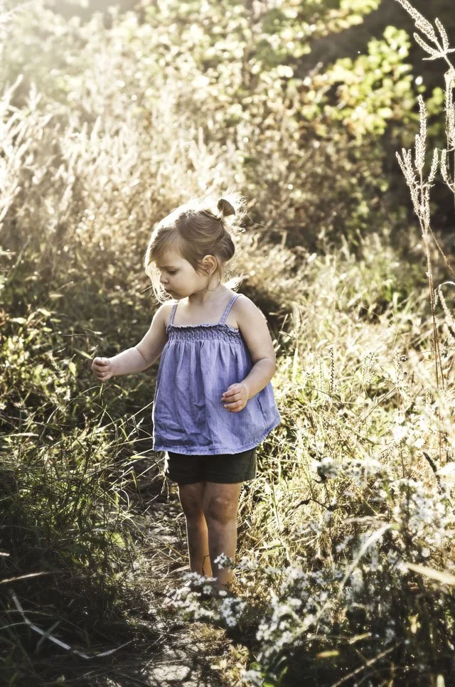 young girl in blue shirt stands on dirt path in field at sunset in summer, clarksville tn, nashville tn, fort campbell ky, photographer, affordable, golden hour, family photographer, milestone, birthday