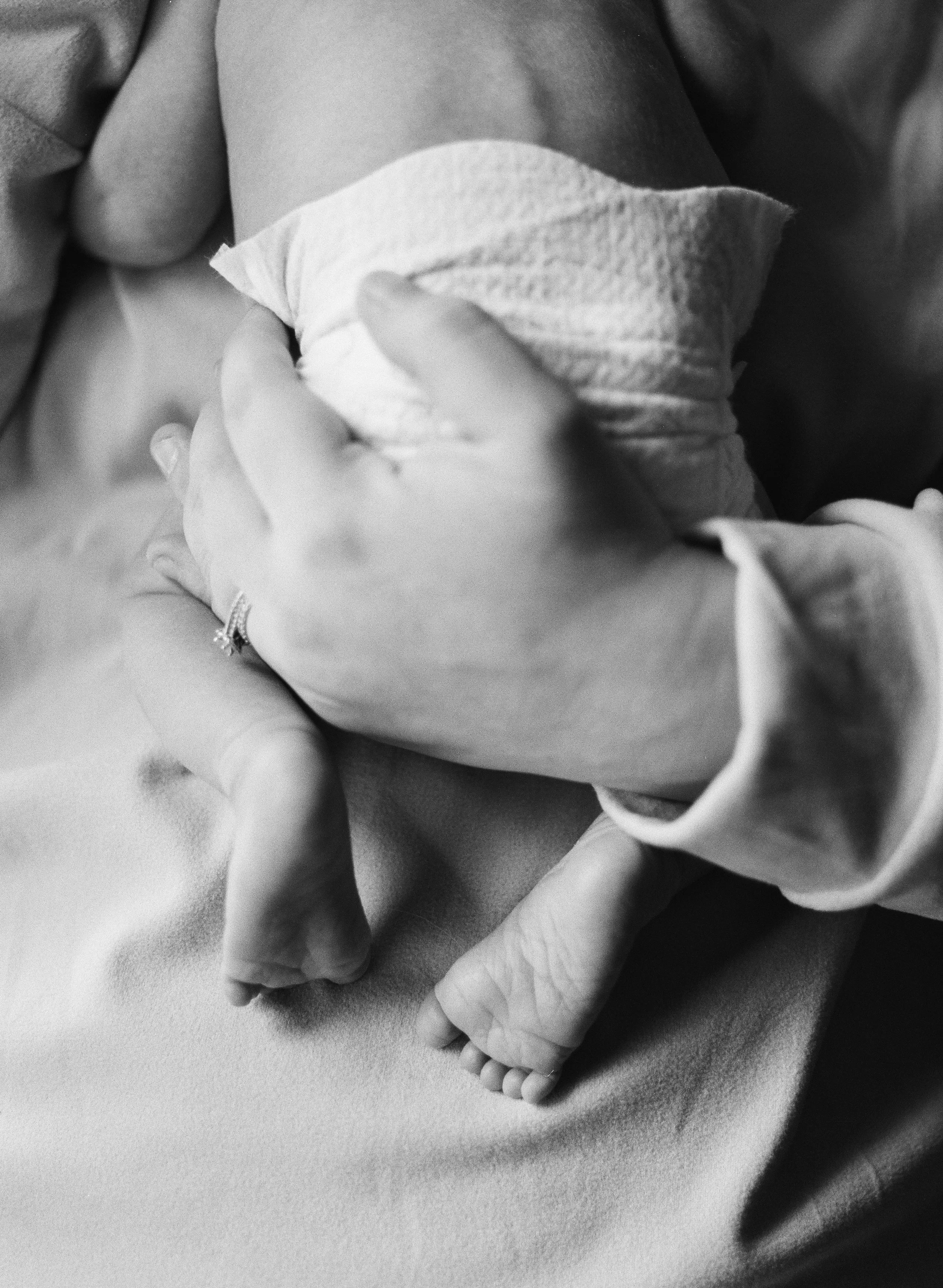 close up black and white portrait of mother holding newborn baby wearing diaper and barefoot, clarksville tn photographer, newborn photographer, in-home newborn photographer, film photographer, family and newborn, documentary newborn photographer