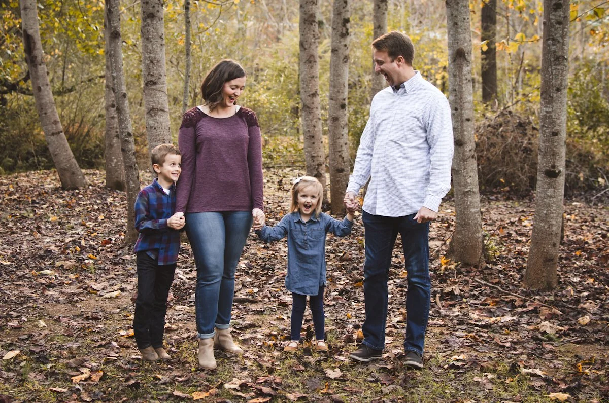 family of four with young boy and girl walk through wooded area with fallen leaves, fall, autumn, family photos, family photographer, photographer, affordable, clarksville tn, nashville tn