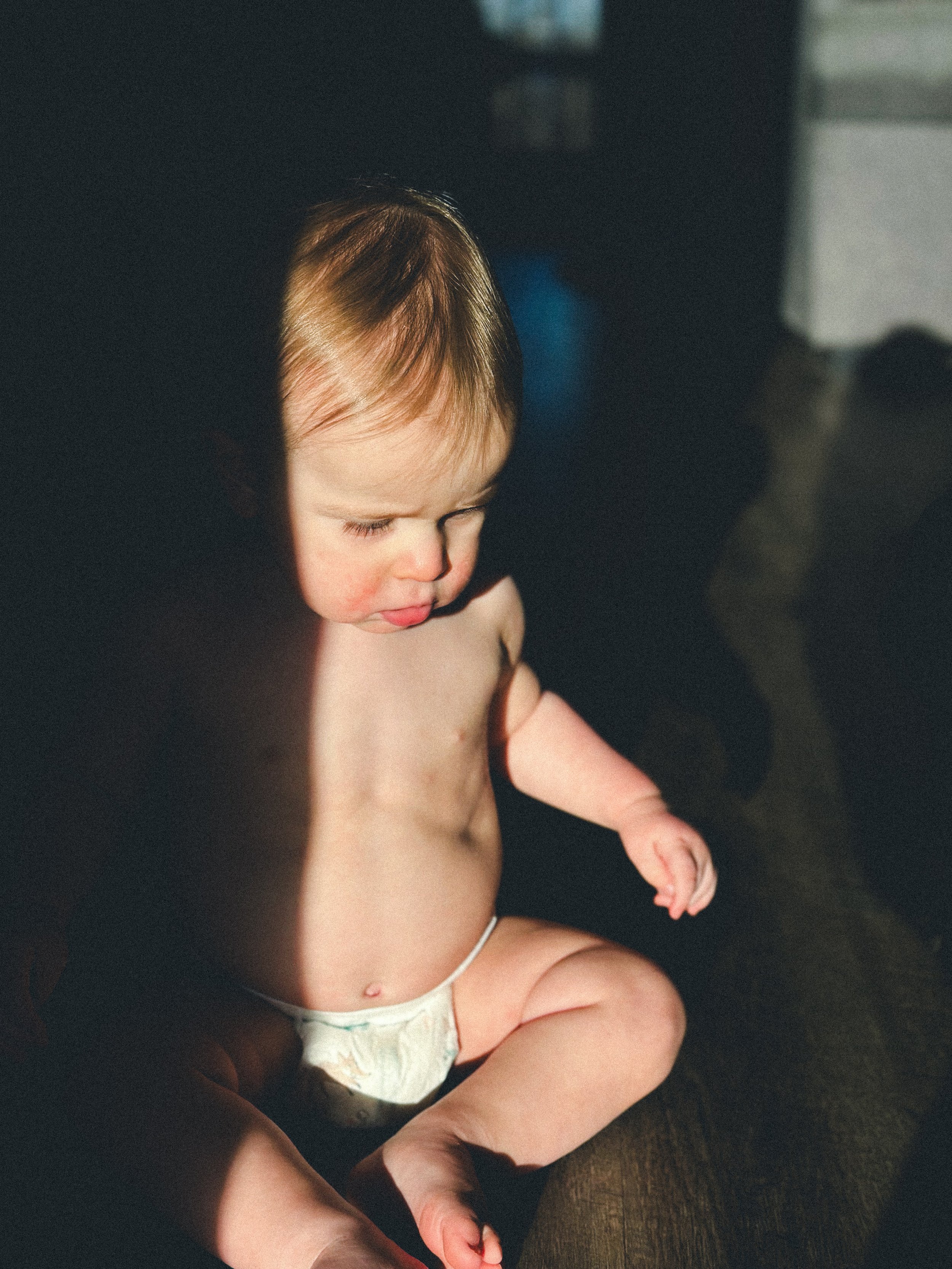 baby boy sits in bright light and shadow on floor of home, clarksville tn, nashville tn, family photographer, documentary family photographer, moody, dark, bold, affordable