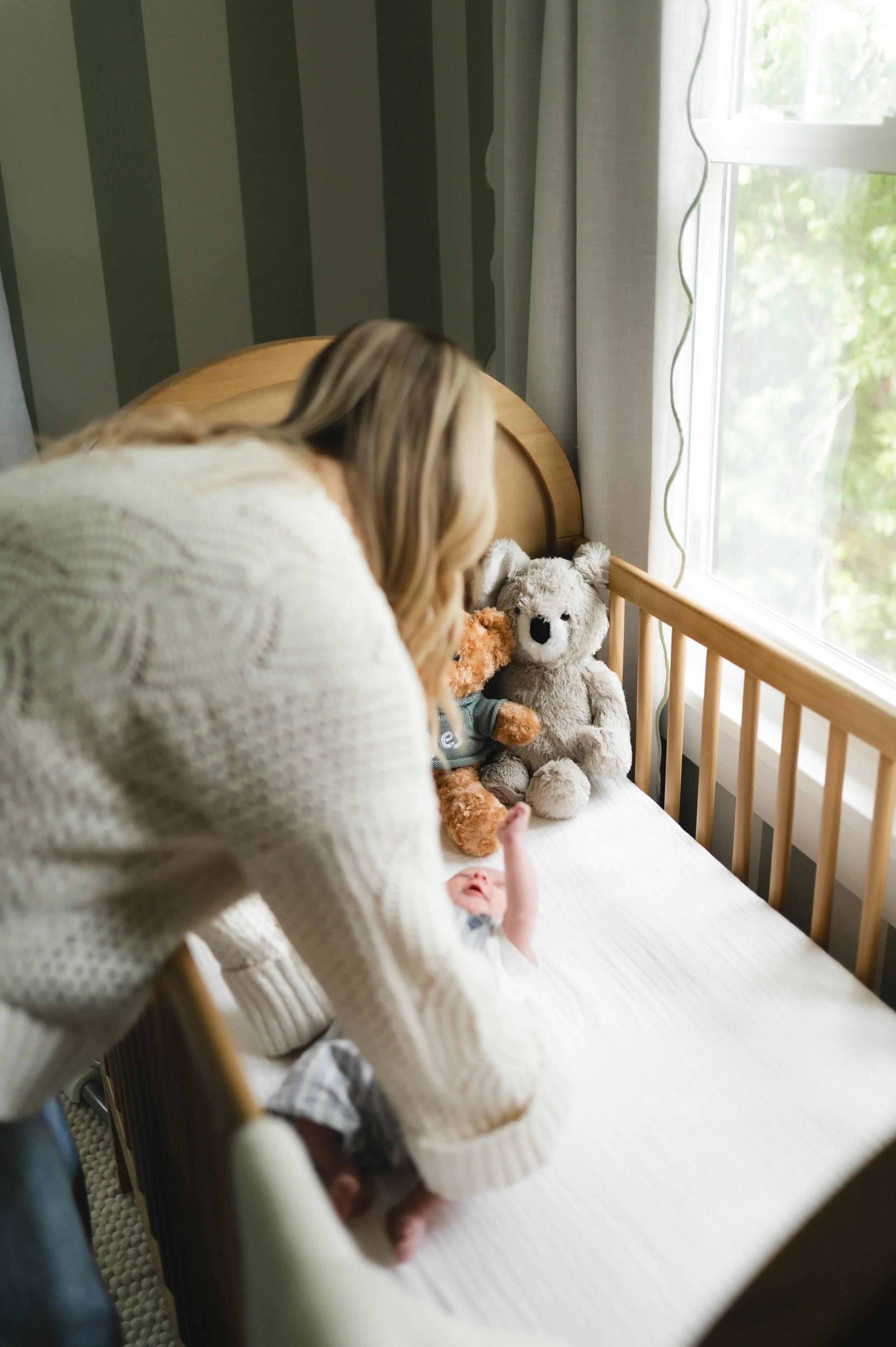 woman picking up baby from crib, newborn photographer, affordable, madison tennessee, clarksville tennessee, nashville tennessee
