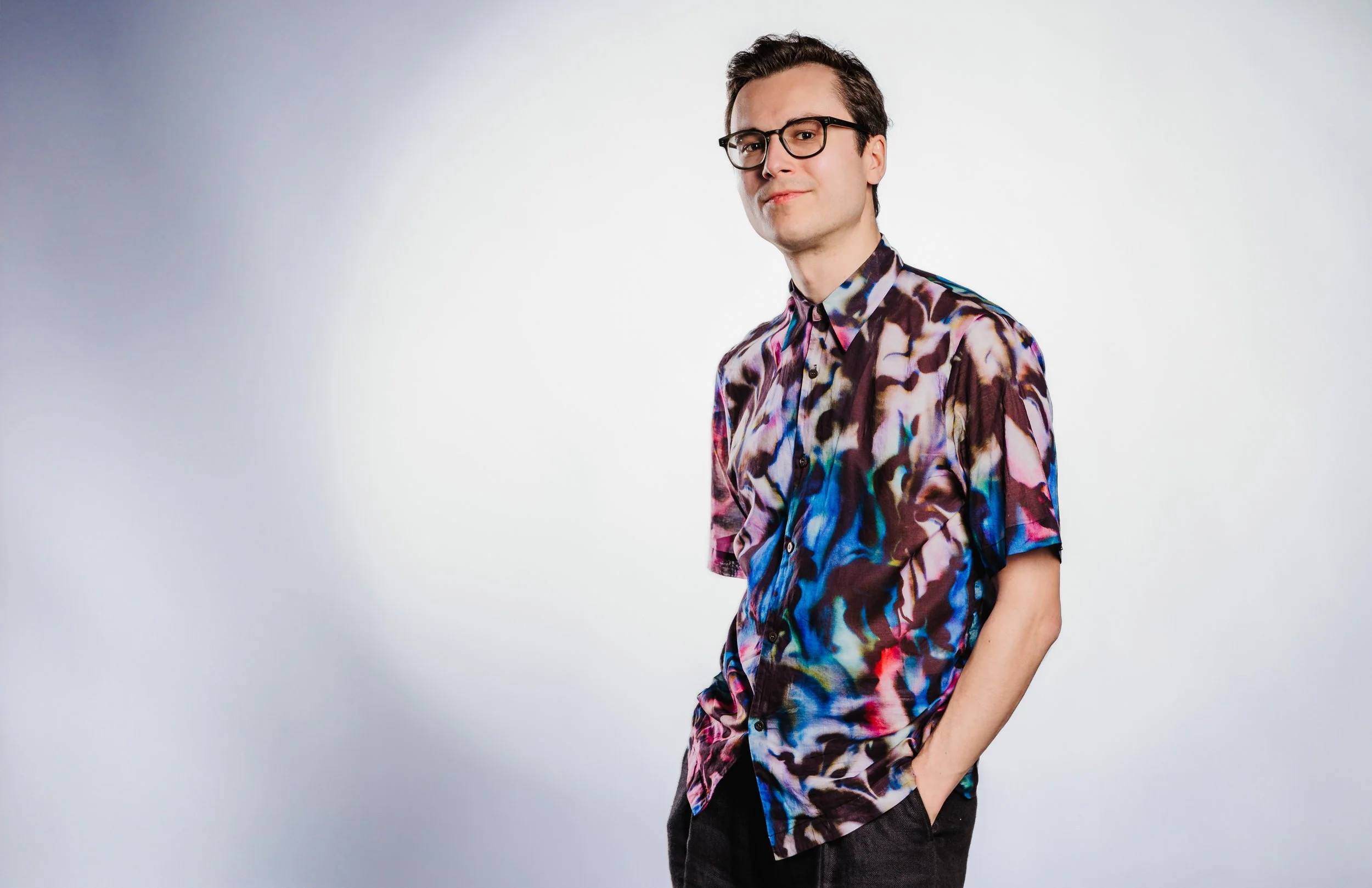 A studio portrait of radio presenter Carlo Siau, captured in a vibrant, colorful shirt.
