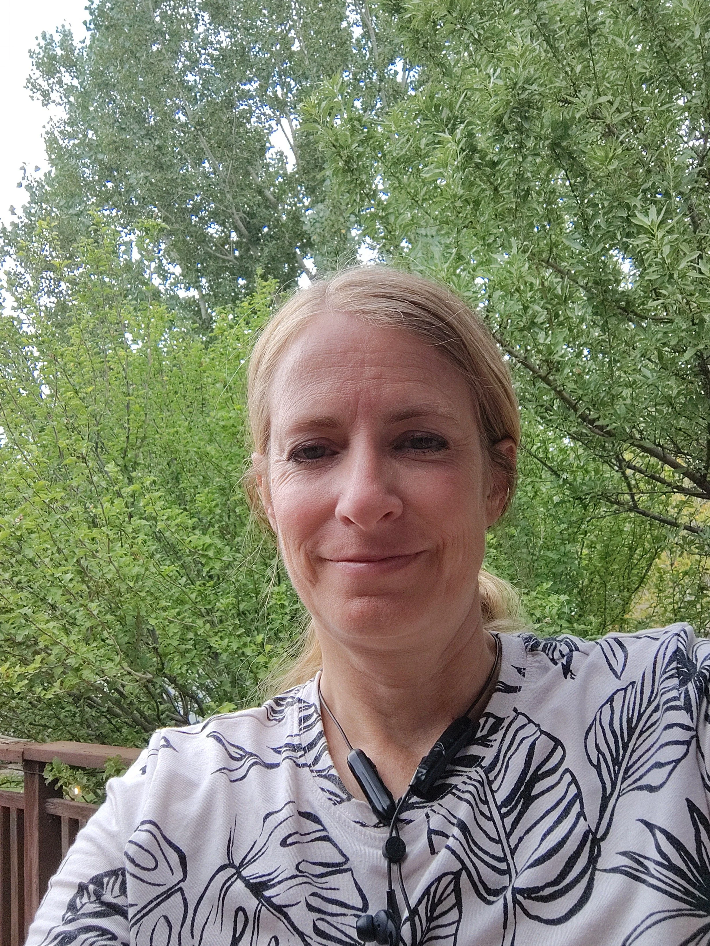 Woman sitting in front of trees smiling