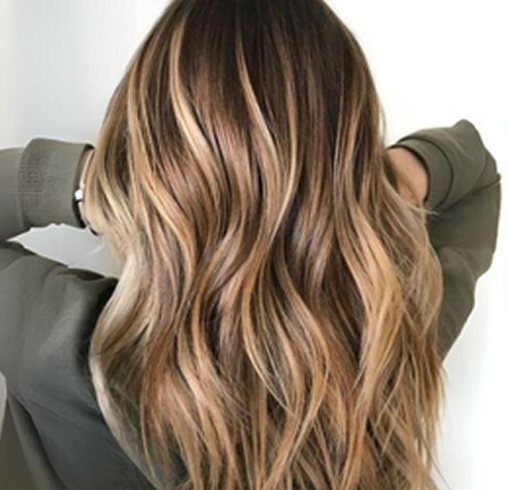 Back of a woman with long, wavy, blonde hair, wearing a green top.