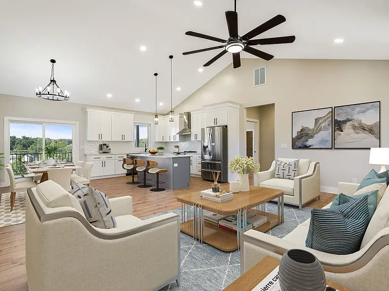 Open-concept living room and kitchen with white cabinetry, stainless steel appliances, a kitchen island with three chairs, and a dining area with a sliding glass door leading to an outdoor balcony.