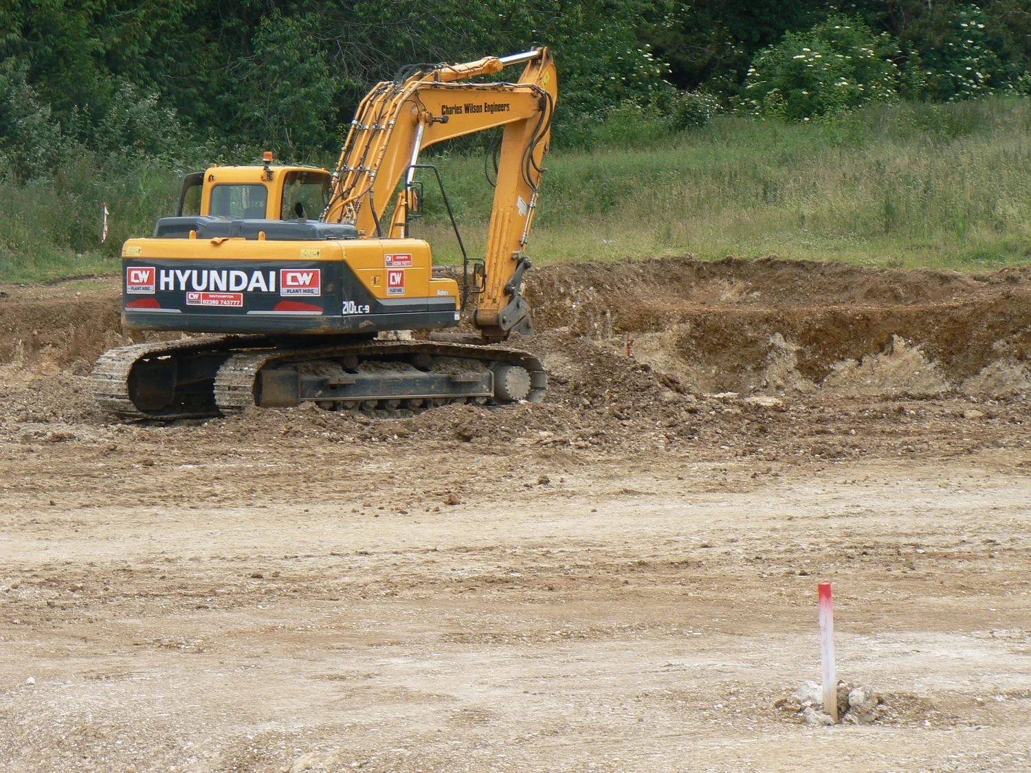 A yellow Hyundai excavator working on a construction site with dirt and soil.