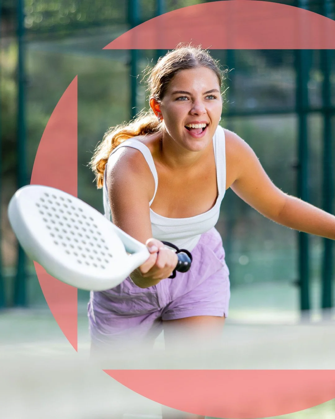 Young woman playing pickleball on an outdoor court, holding a paddle and smiling.