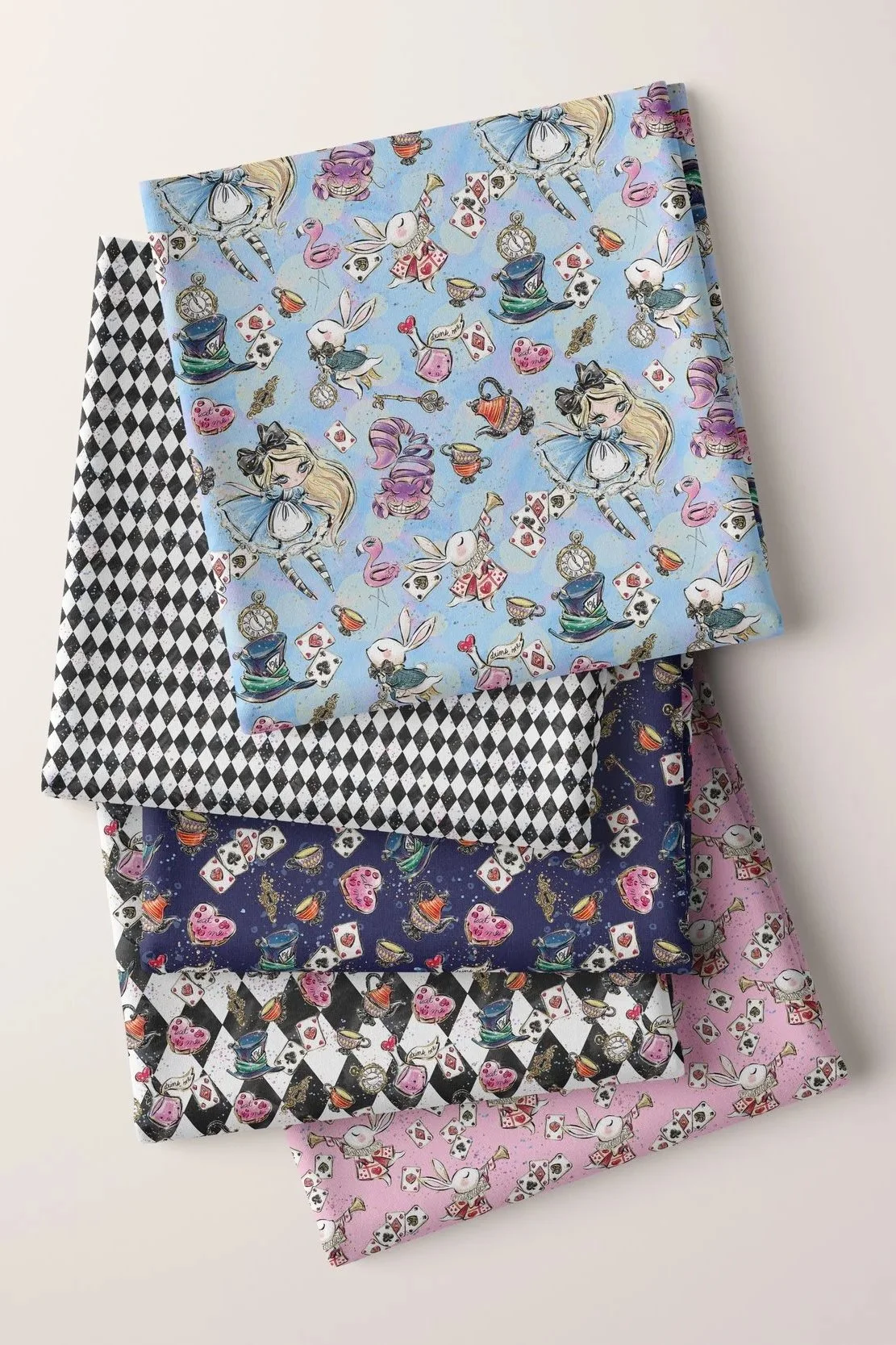 Five folded fabric pieces with Alice in Wonderland-themed prints, arranged in a fan shape on a white surface, with two pink-headed sewing pins nearby.