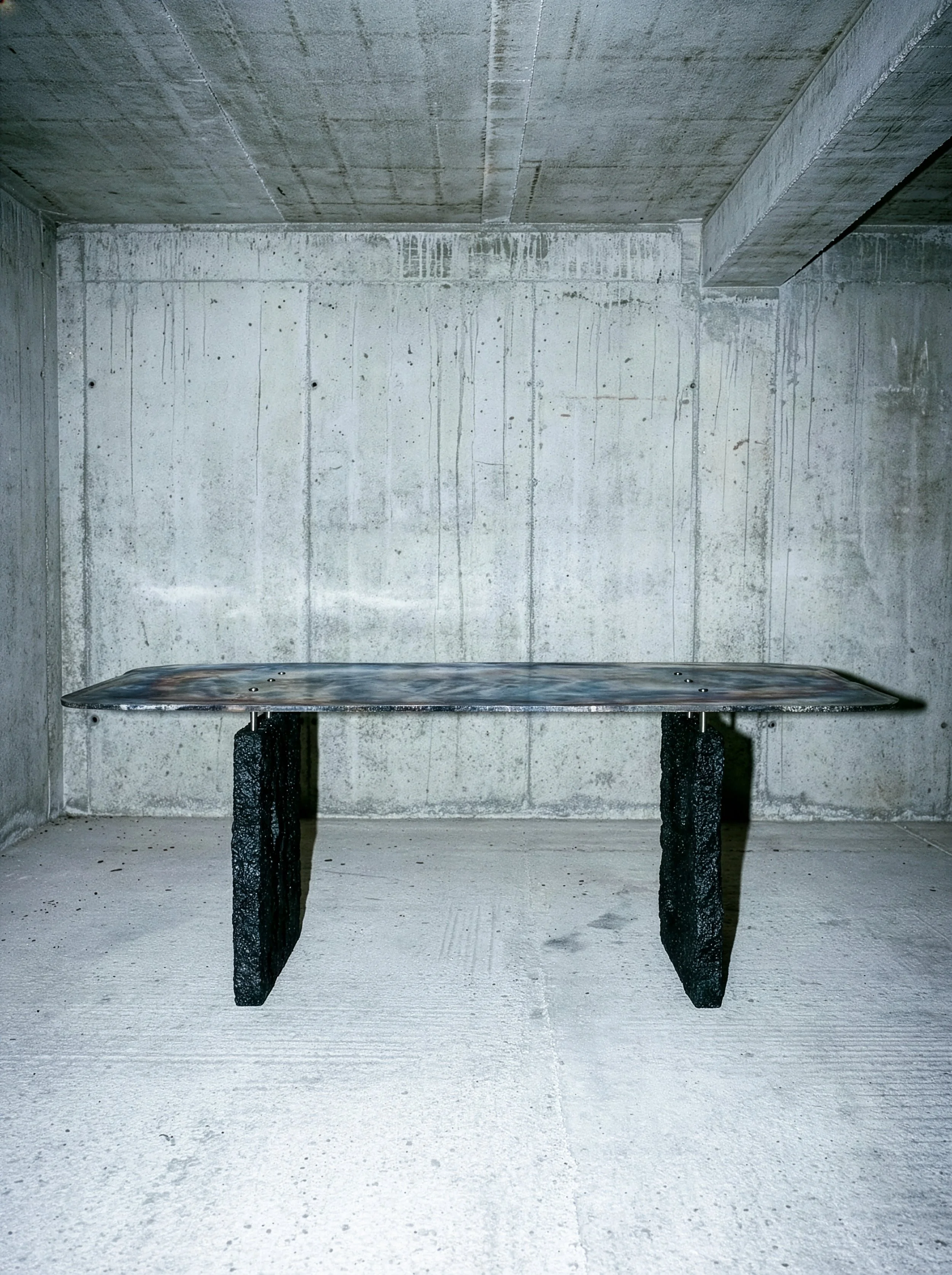 Banc en béton dans une pièce aux murs et plafond en béton brut.  PAUL HARDY