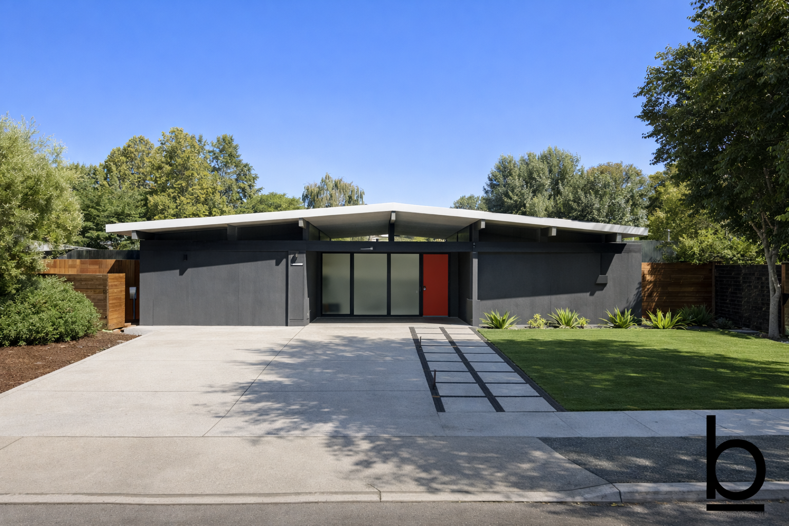 Front view of a modern single-story house with black exterior walls, a white flat roof, a large glass sliding door, and a red door, surrounded by a green lawn, plants, and trees.