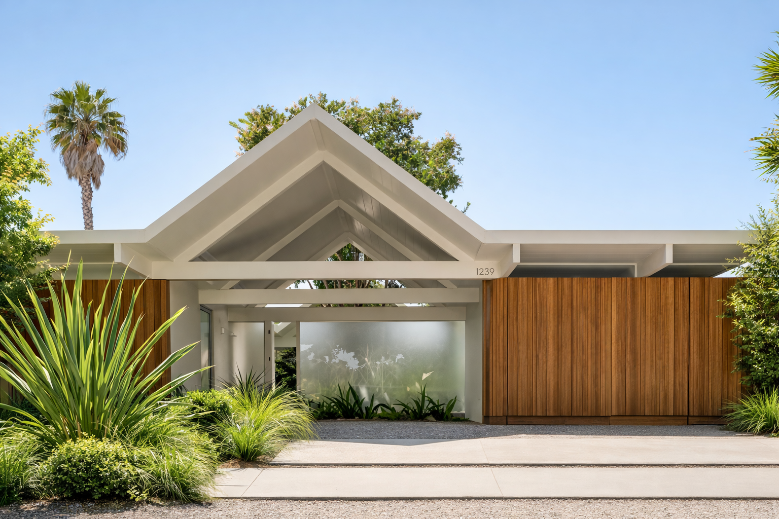 Front view of a modern house with a white roof, wooden fence, and lush green plants in the front yard, under a clear blue sky.