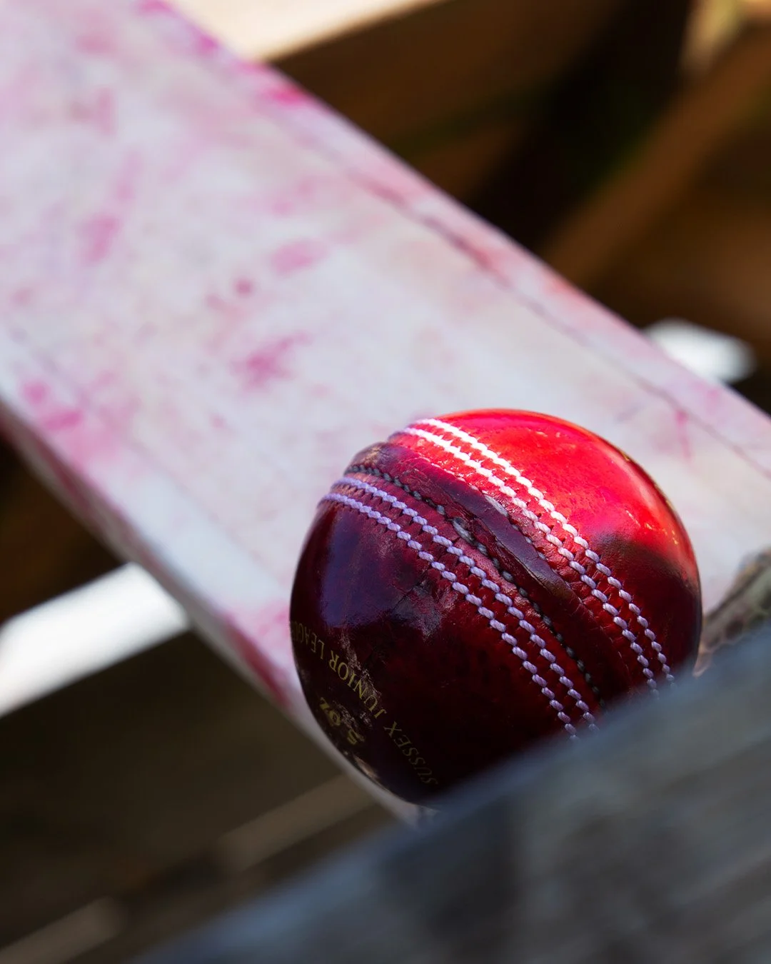 cricket ball with a cricket bat in background