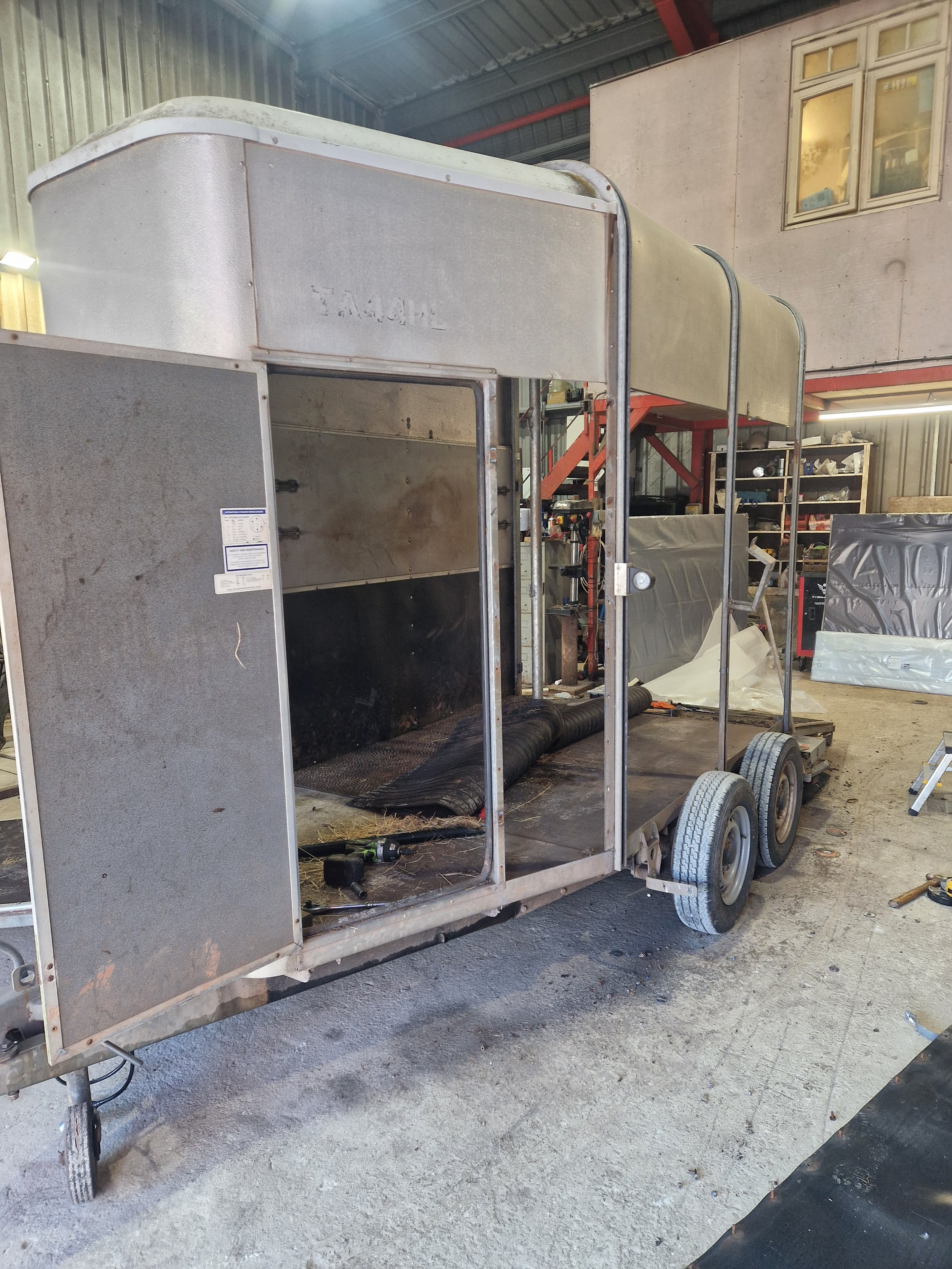 An empty, partially assembled food truck with a metal frame and wheels inside a workshop.