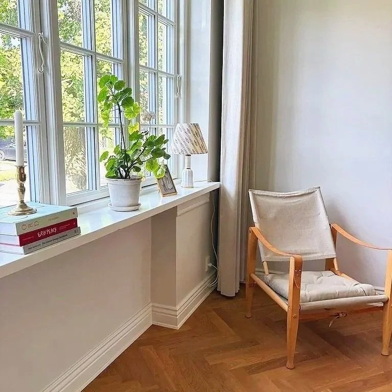 En lys stue indrettet til private med sildebensparket og danske designmøbler og en hyggelig vindueskarm.