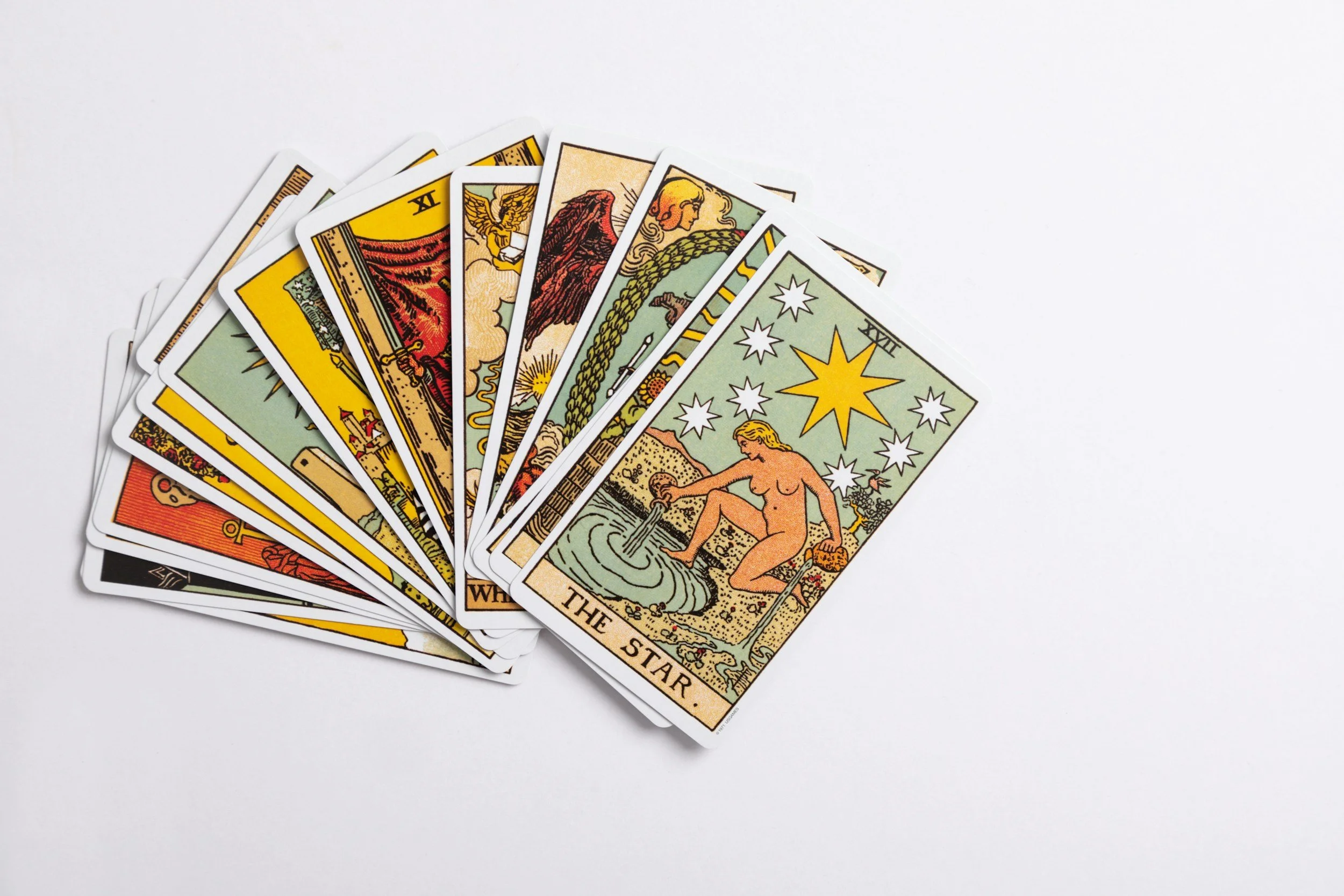 Image of about a dozen tarot cards fanned out, overlapping, on a white background. The Star tarot card is the top one. The deck is the Smith-Waite Centennial Deck