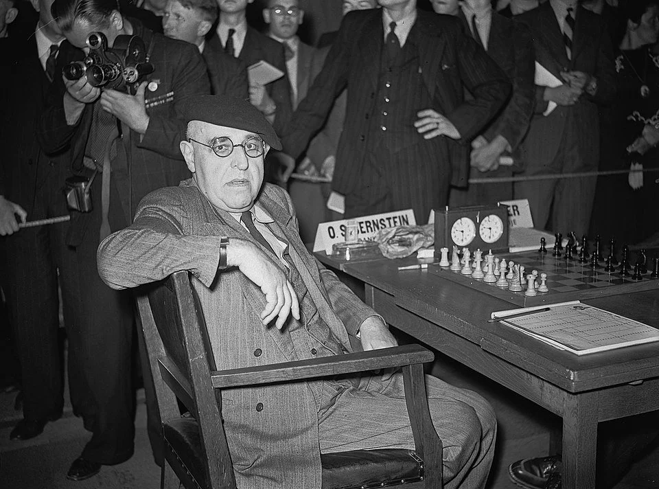 Ossip Bernstein having his picture taken at a chessboard