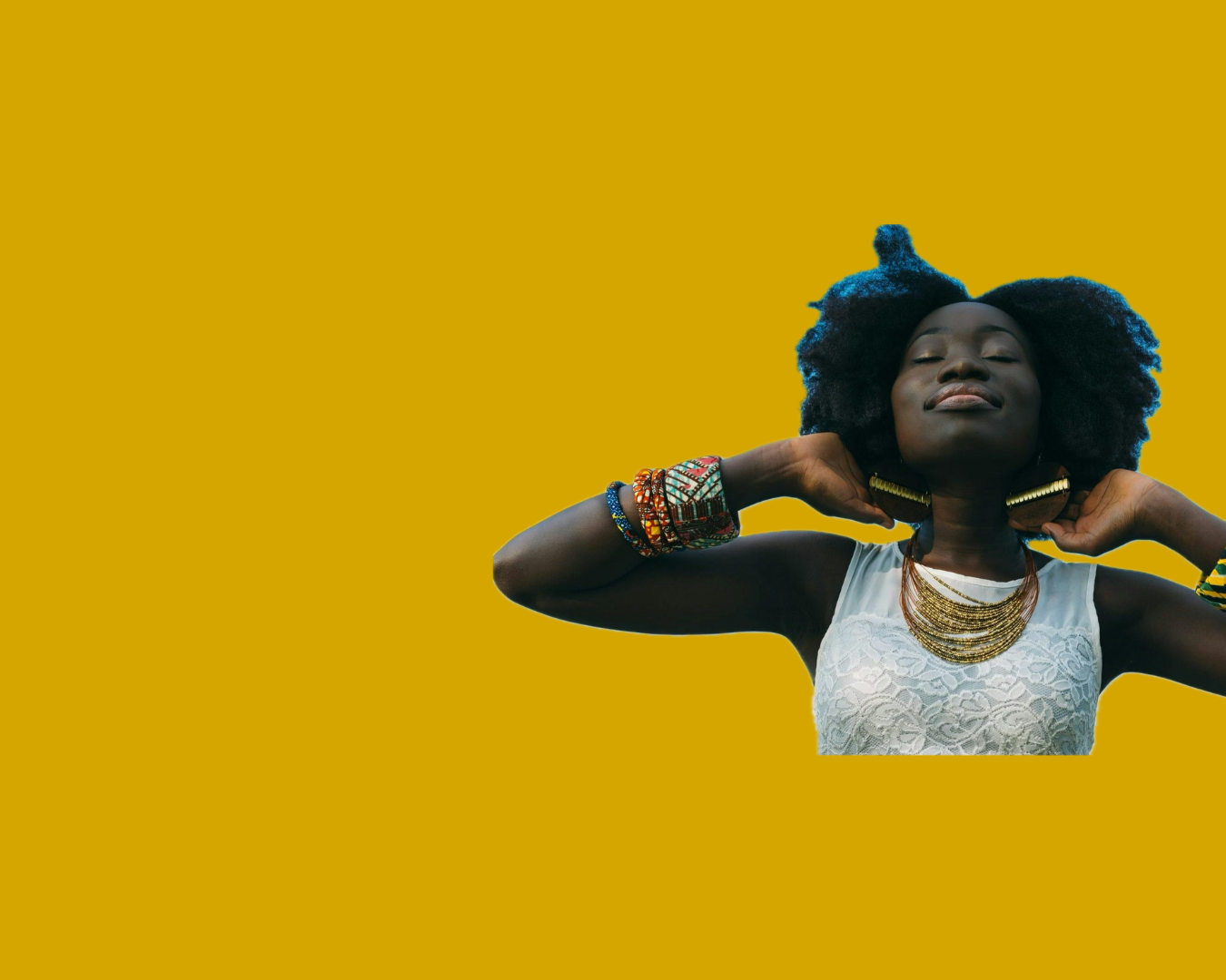 A woman with dark skin and voluminous natural hair stands against a mustard yellow background. She wears a white lace sleeveless top, layered gold necklaces, large earrings, and multiple colorful beaded bracelets. She is holding her hair with her hands near her ears and has a serene, confident expression.