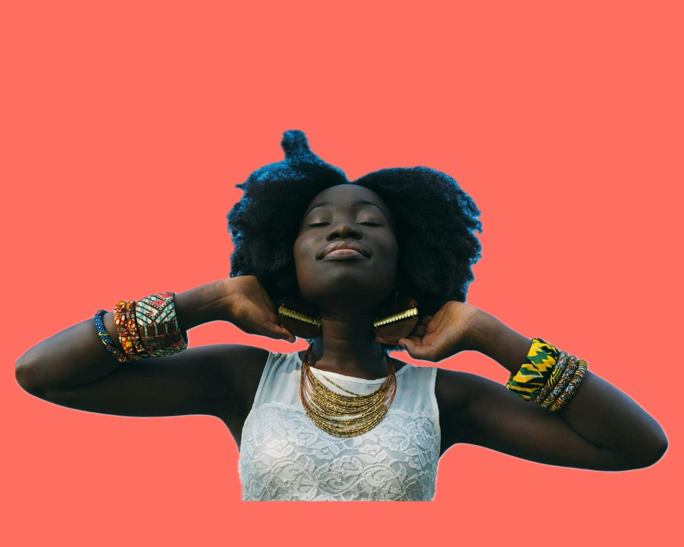 A Black woman with natural hair styled in an afro, wearing a white lace top, gold jewelry, and colorful bracelets, holding her hands behind her neck with eyes closed against a coral background.