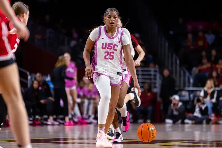 Kara Dunn, former guard on USC women's basketball team, pictured playing against Wisconsin in a pink and white jersey.
