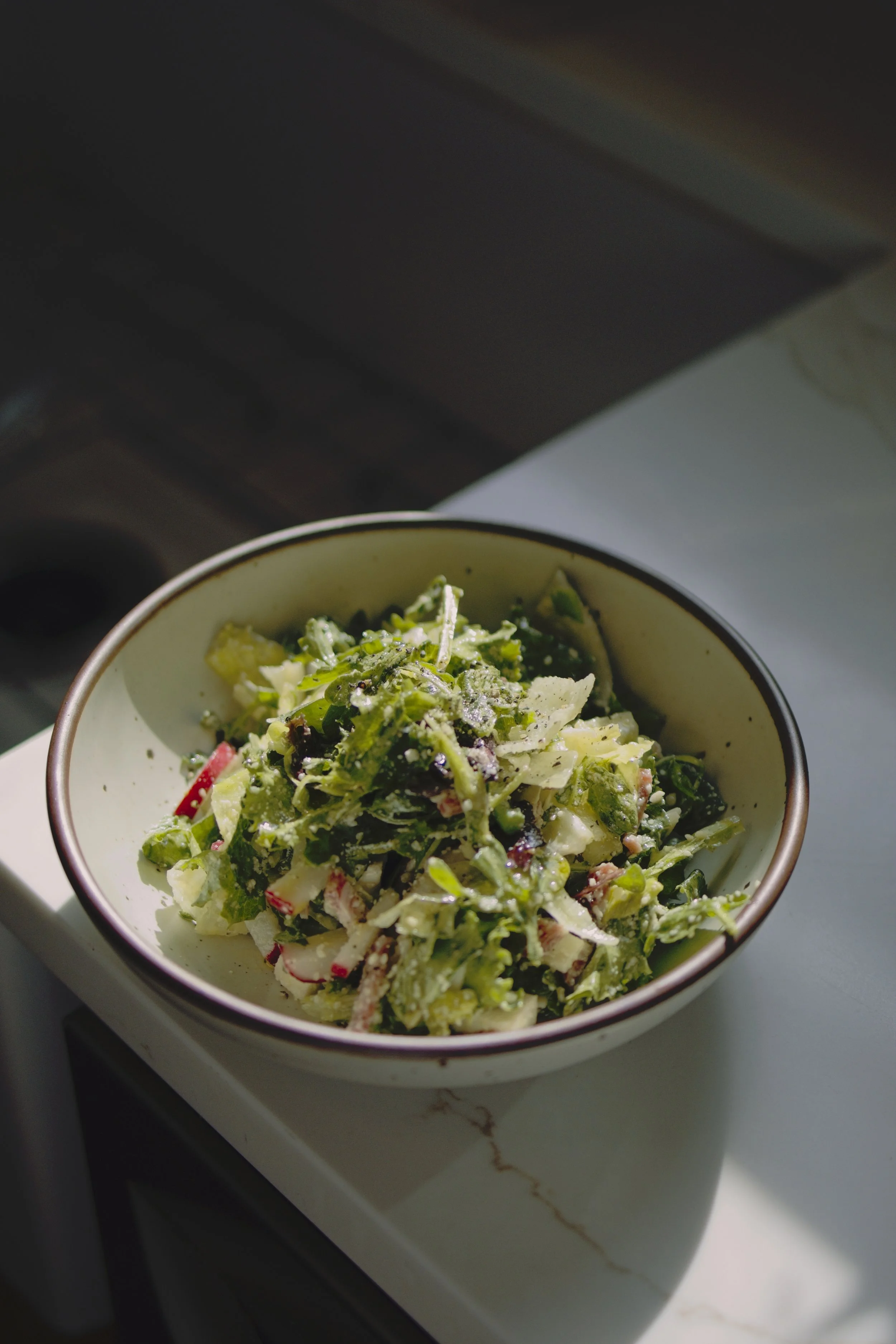 A bowl of fresh salad with mixed greens, sliced radishes, and grated cheese in Somerville, NJ