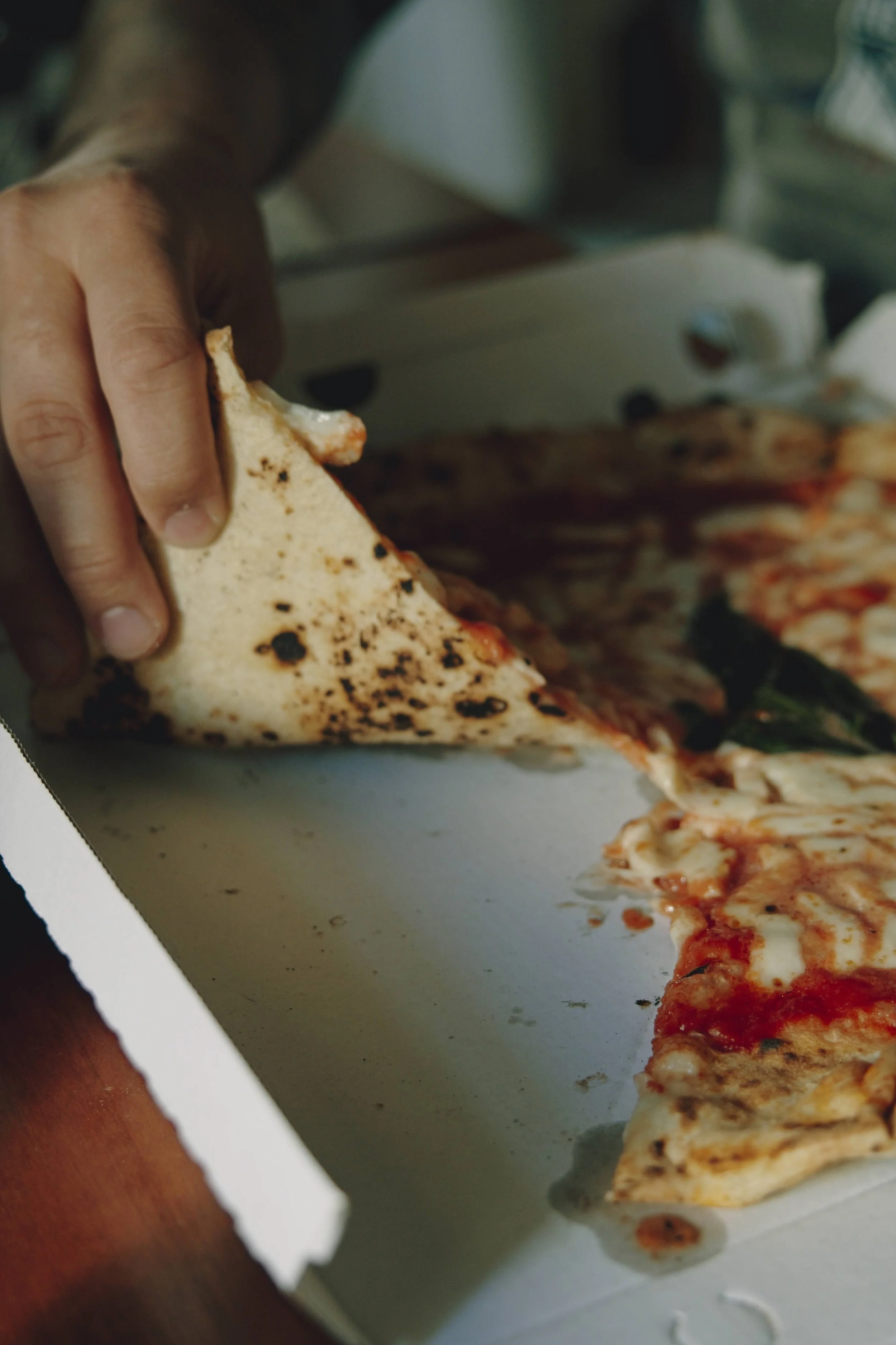 Person picking up a slice of pizza in Naples, Italy