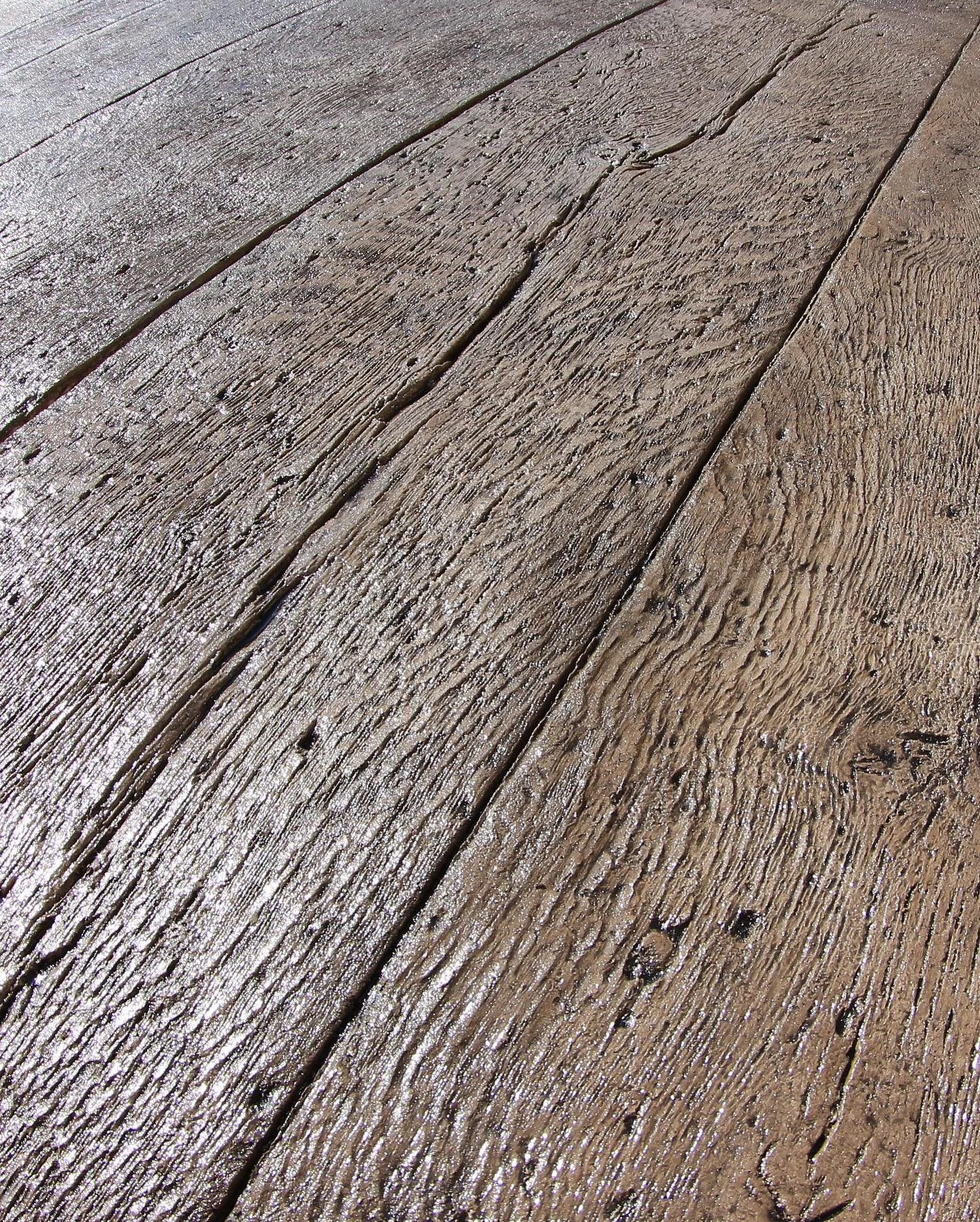 Close-up image of a weathered wooden surface with visible grain, cracks, and small holes.