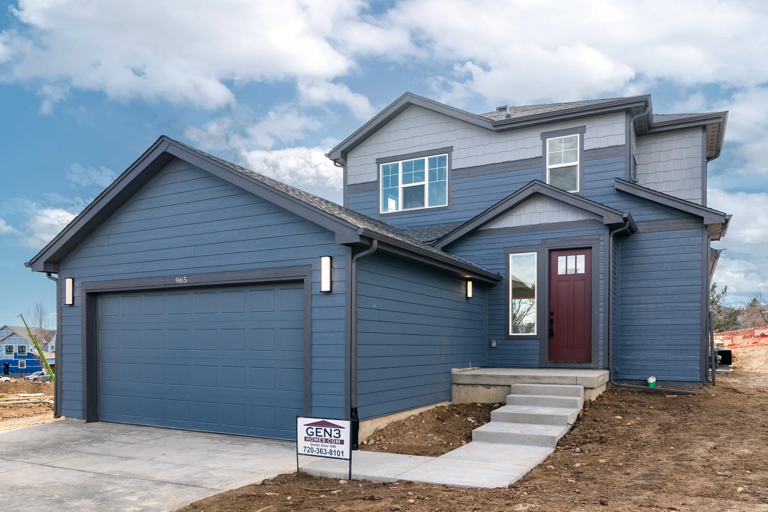 New two-story blue house with a garage and front steps, under construction, with a sign for Gen3 Homes in front. Marshall Fire rebuild in Louisville, Colorado