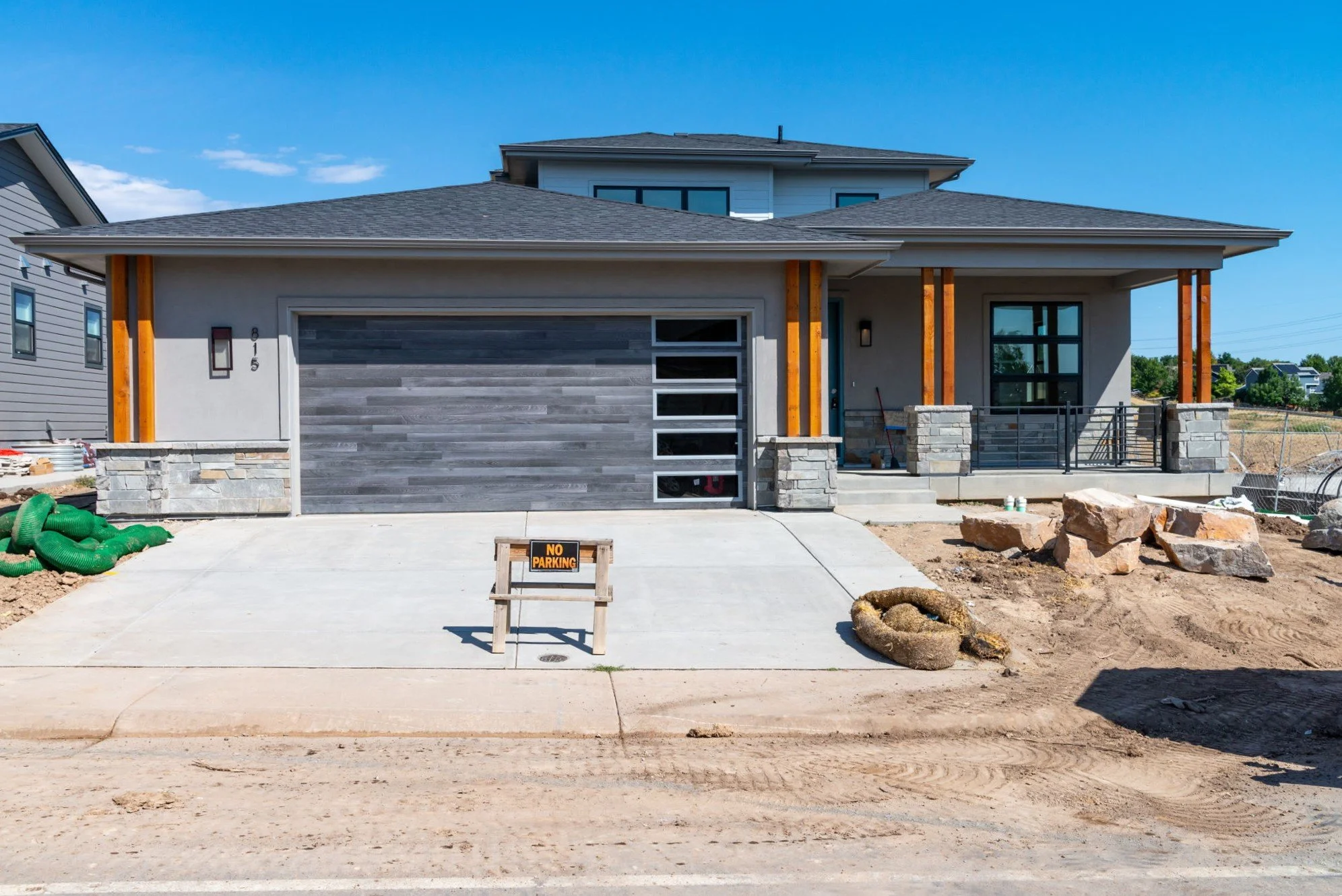 Newly constructed modern house with a concrete driveway, stone accents, and a partially completed front yard. Marshall Fire rebuild project in Louisville, Colorado