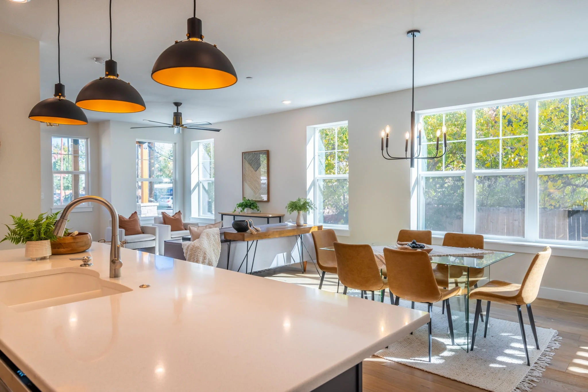 Bright, open-concept living and dining area with large windows, modern lighting, and cozy furniture.