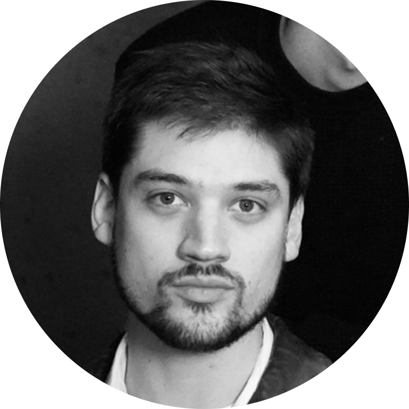 Black and white portrait of a young man with short hair and a beard, looking directly at the camera.