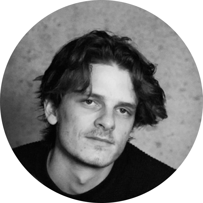 Black and white portrait of a man with wavy hair and a slight smile, looking at the camera.