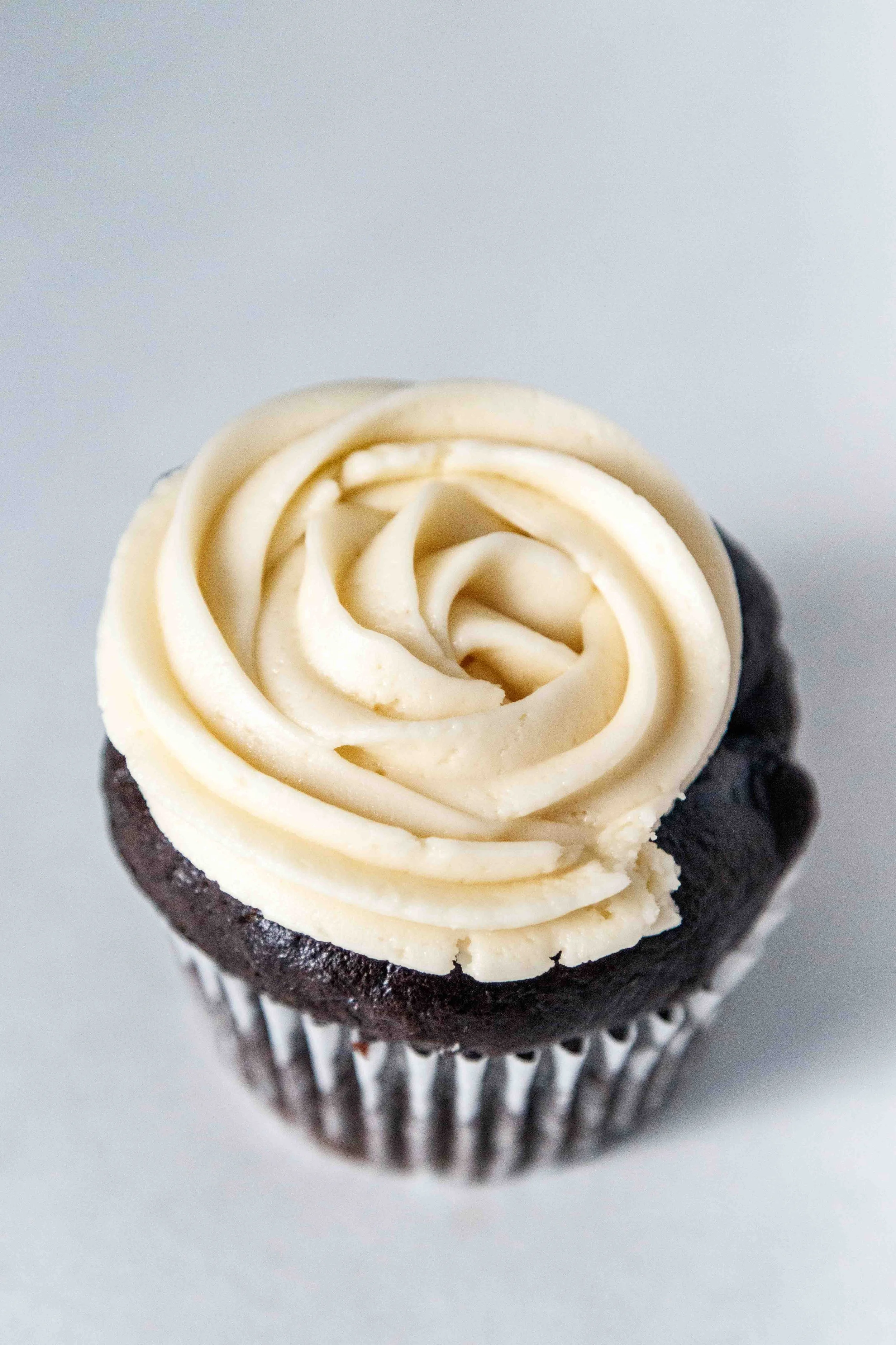 Chocolate cupcake with white frosting swirled in a rose pattern on top.