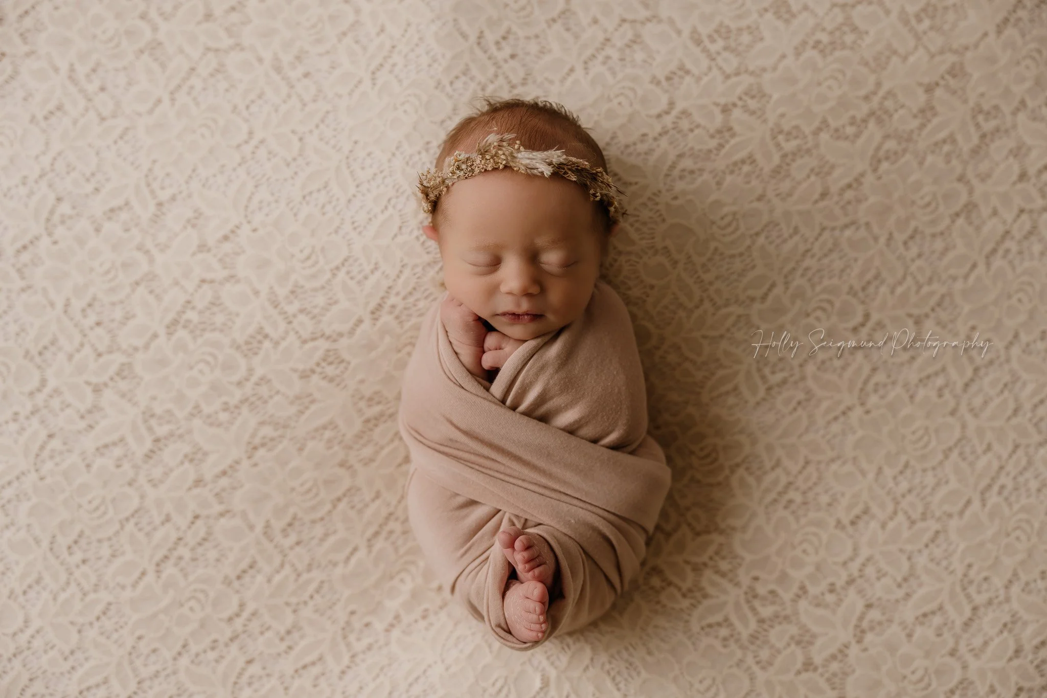 Newborn baby girl on a pink lace backdrop in a photo studio in Central Texas