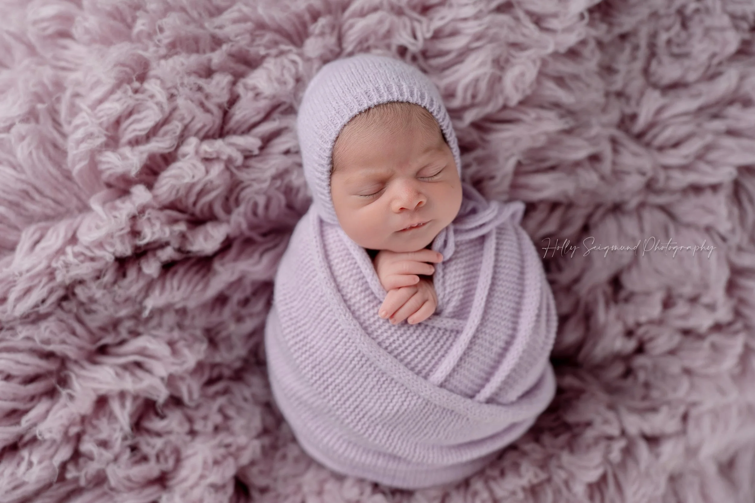 Newborn baby girl wrapped in a purple wrap during a newborn session in Elgin, Texas