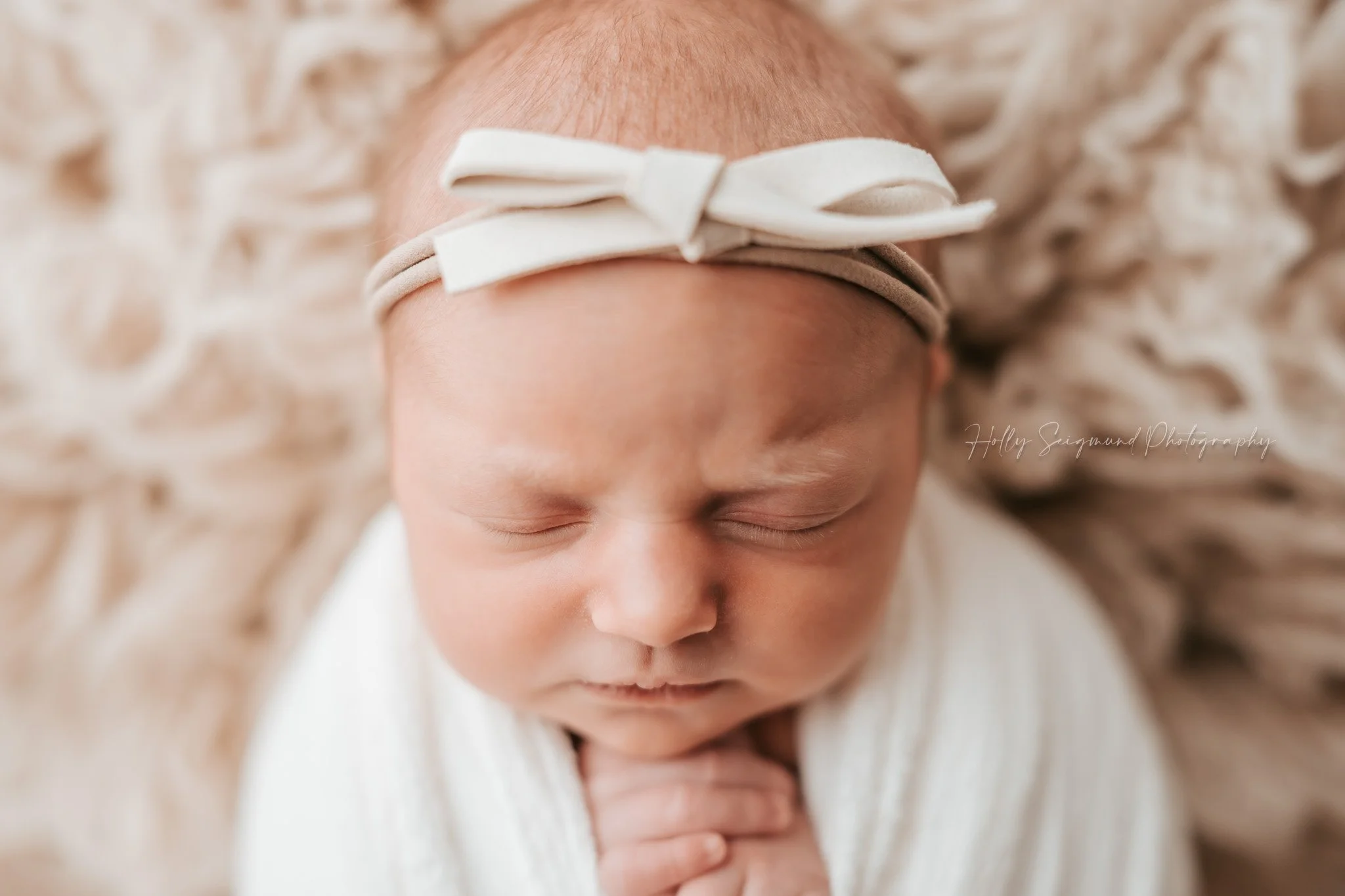 Lee county newborn with white bow on Suede Tan Flokati