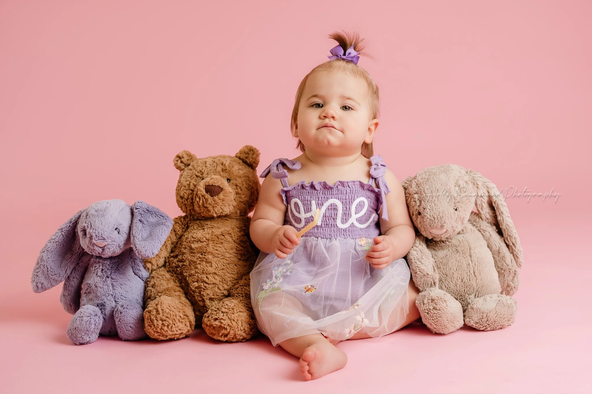 Girls first birthday photos with her stuffed animals in a studio with lights on pink paper in Lexington, Texas