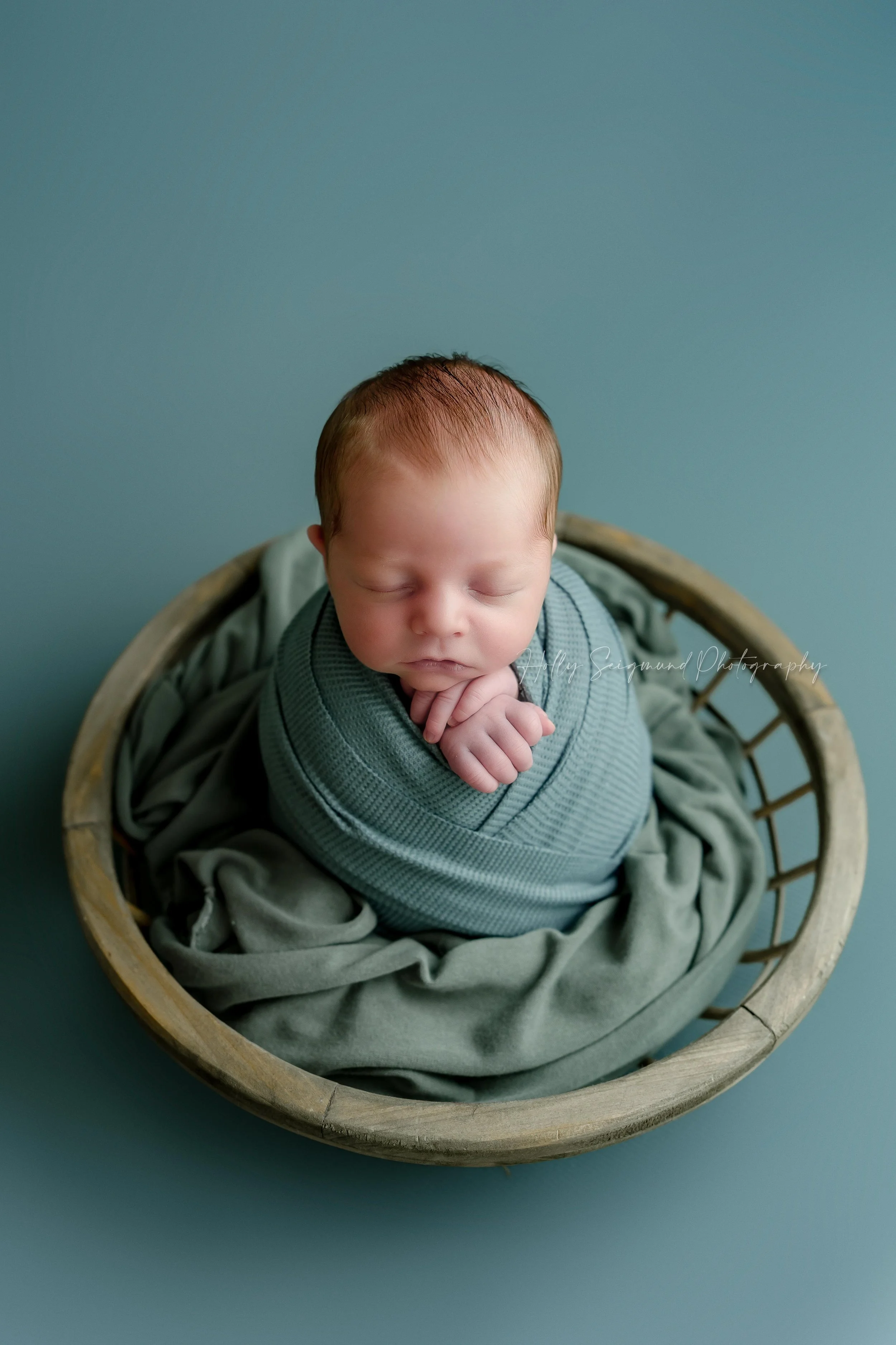 Wrapped newborn baby boy posed in a wooden bowl with turquoise accent colors in Lee County Texas