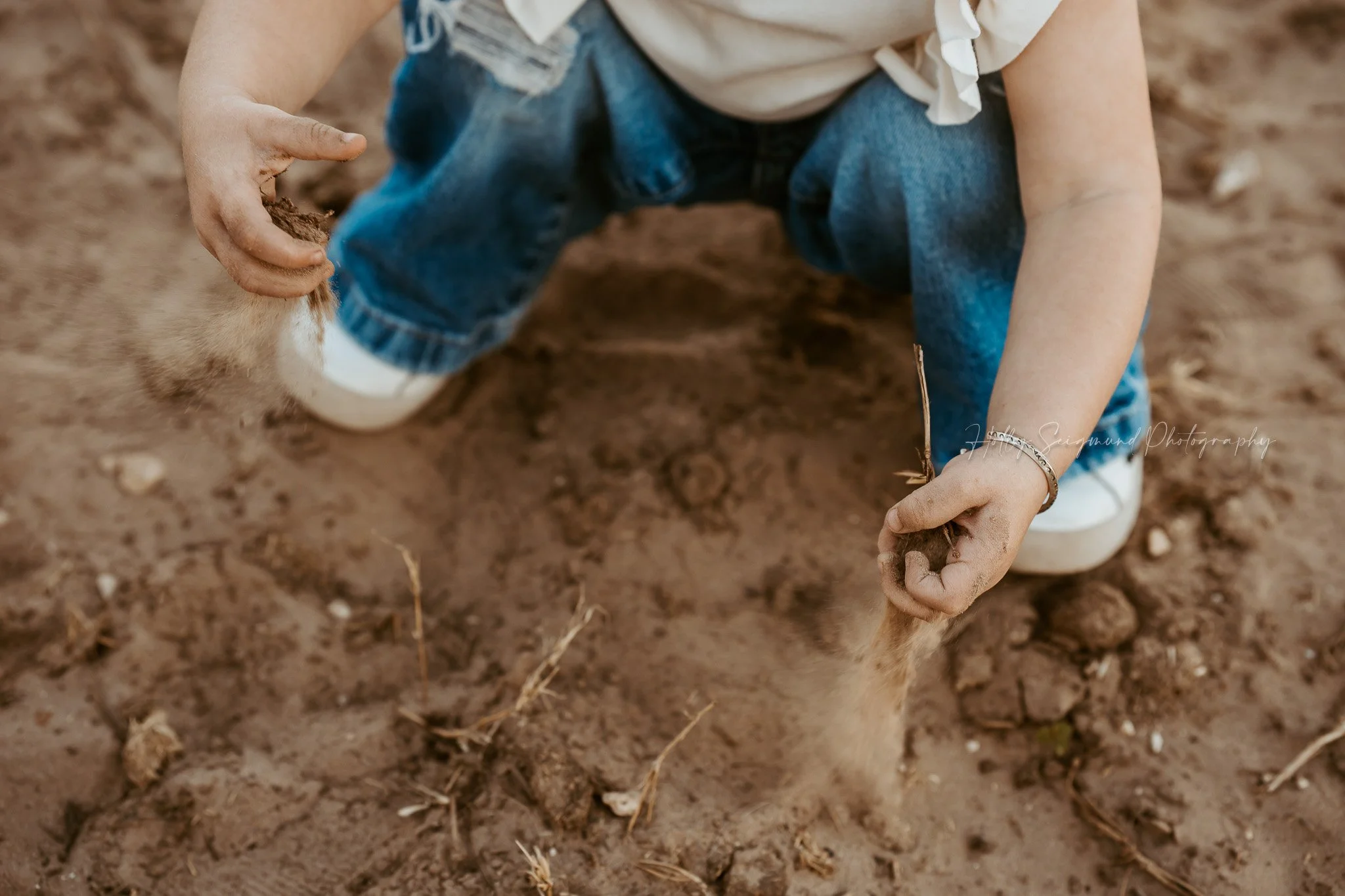 girl enjoying dirt during country-themed birthday session in the Texas countryside