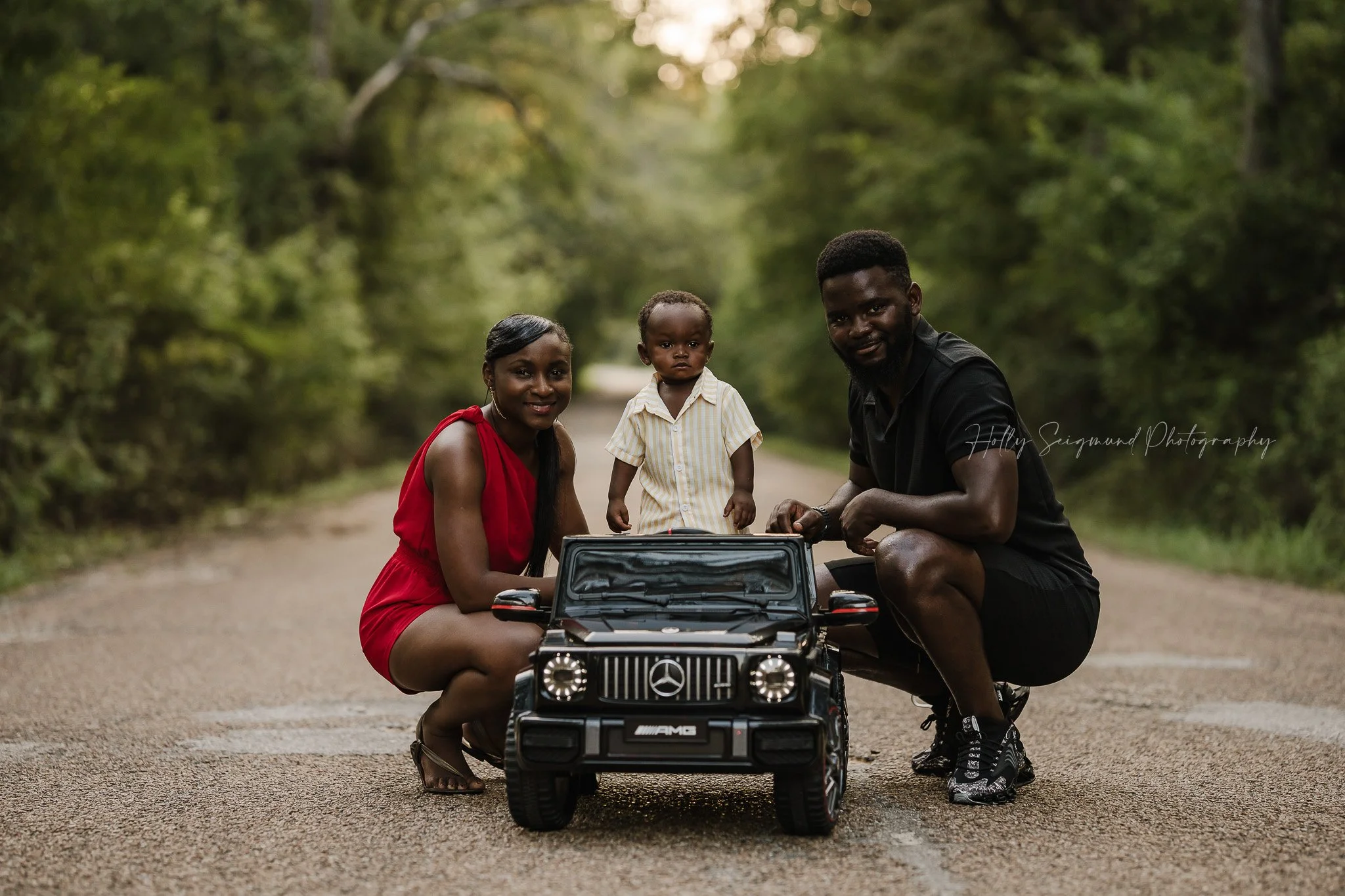 Boy's first birthday photo in his toy car with his family in Central Texas