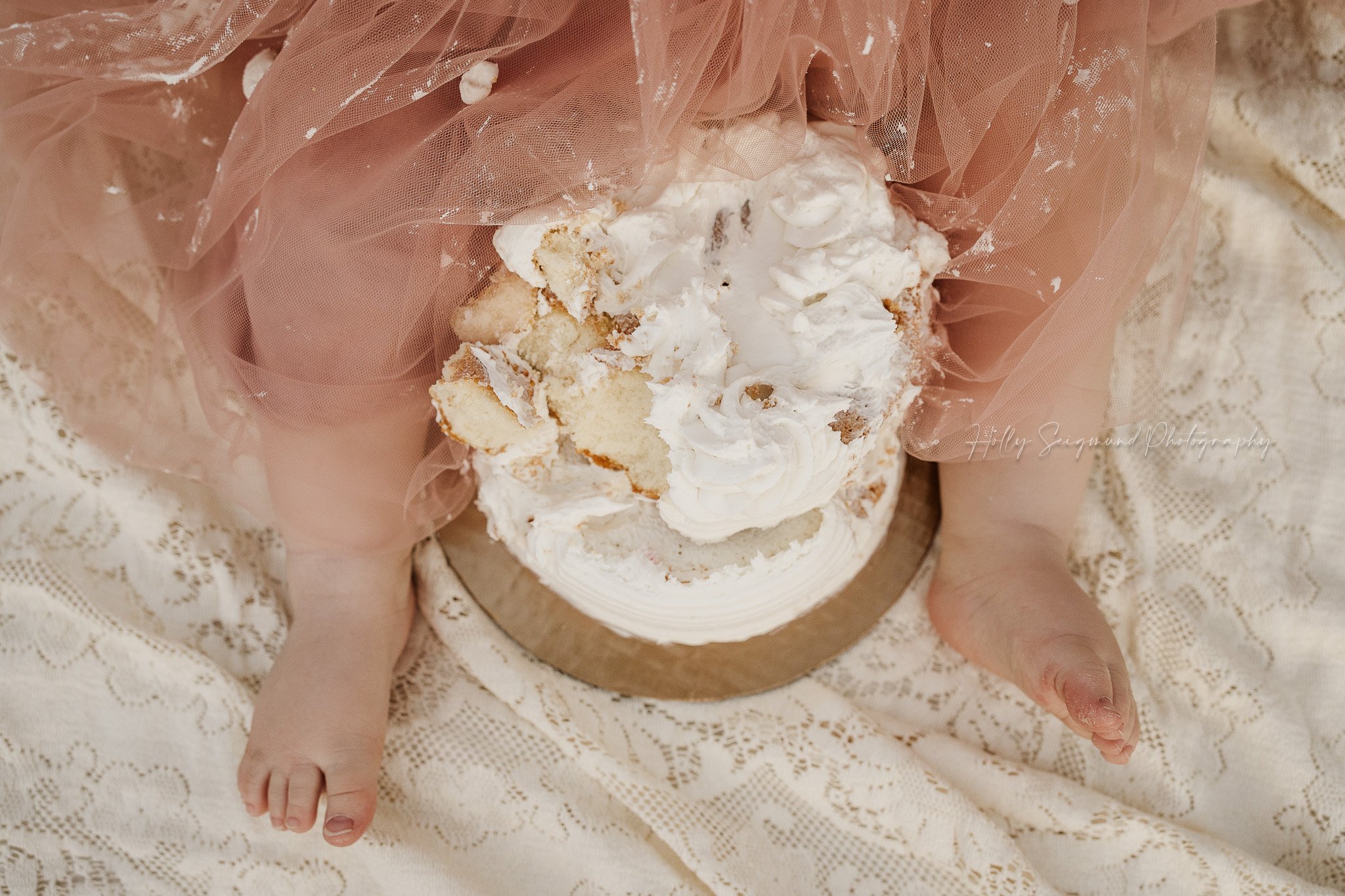 Boho style smash cake photo of the messy cake and baby toes on vintage linens in Lexington, Texas