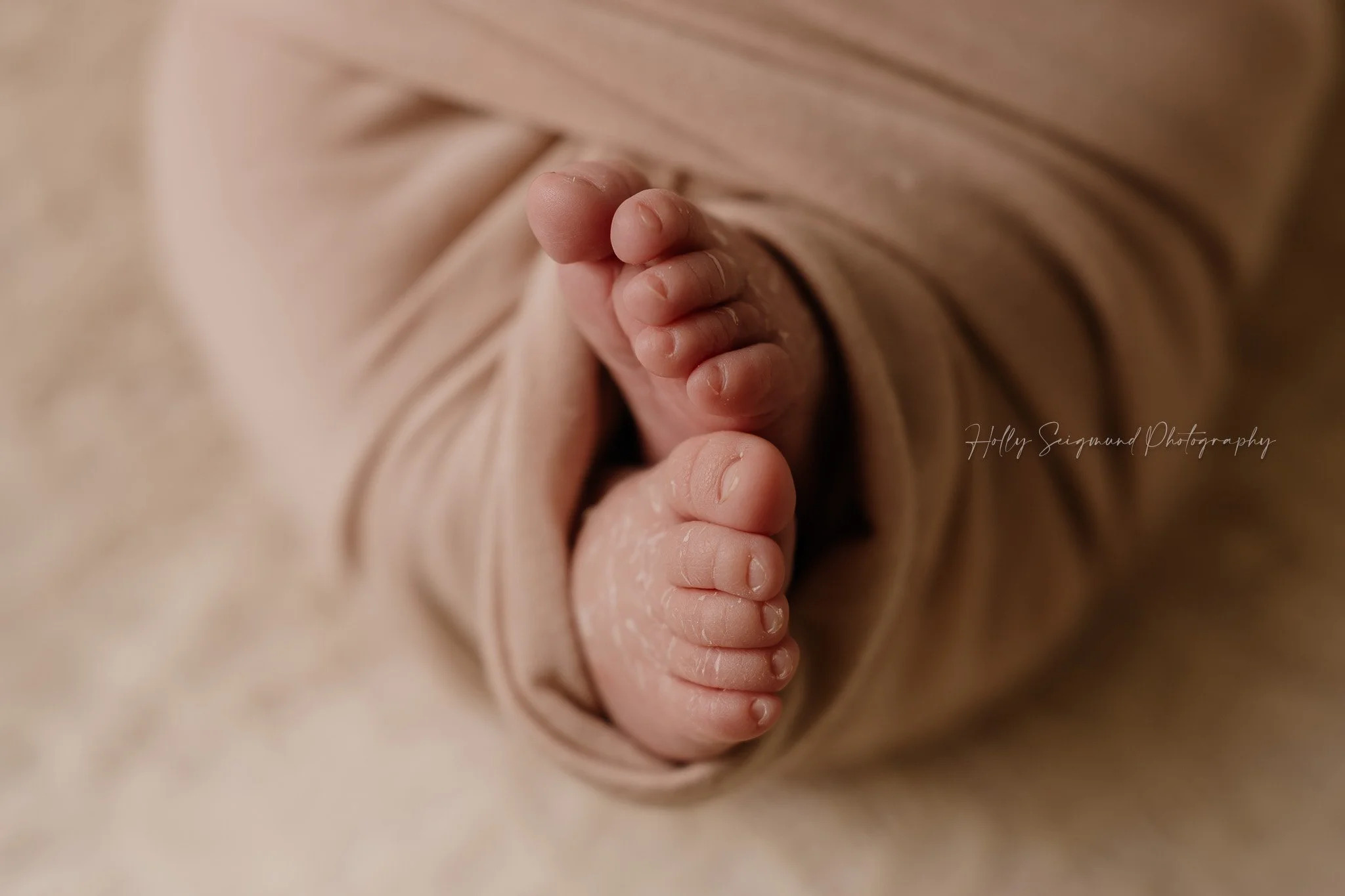 Baby toes wrapped in a pink wrap on a lace backdrop during a photoshoot in Central Texas