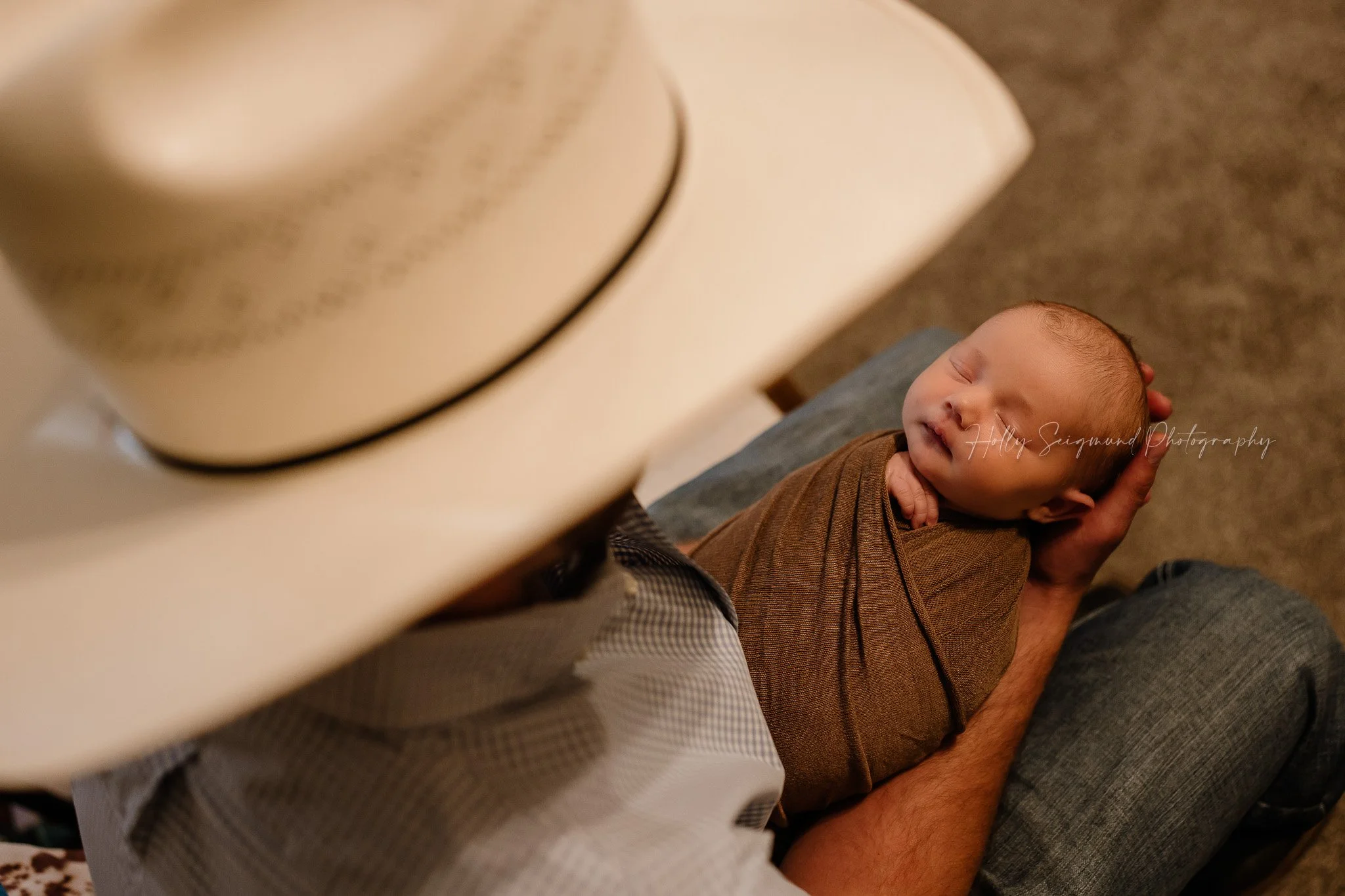 Dad's view over the cowboy hat of his newborn during in-home newborn session in Central Texas