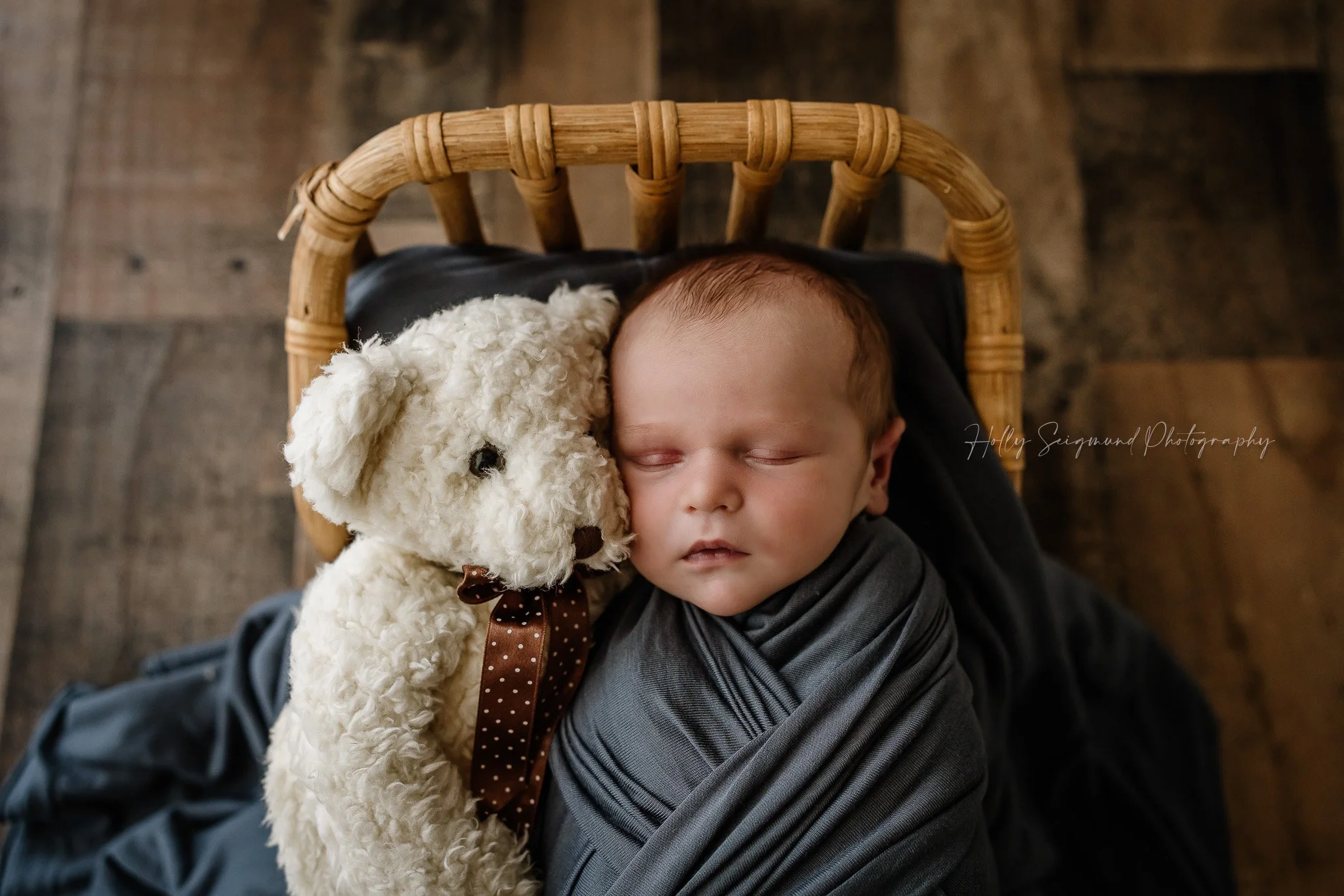 Newborn and teddy bear with a blue wrap in a wooden bed in Lee County Texas