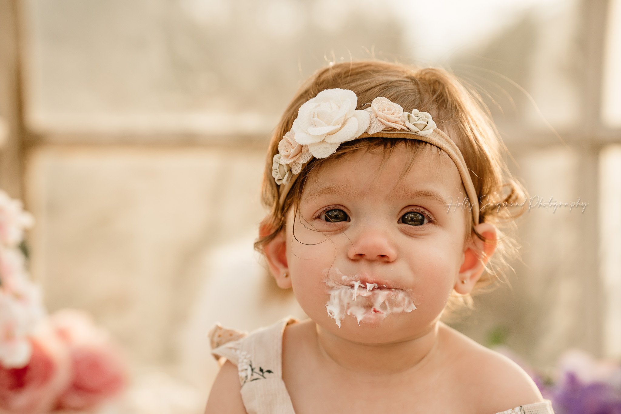 One year old girl with icing on her face during a smash cake session in Central Texas