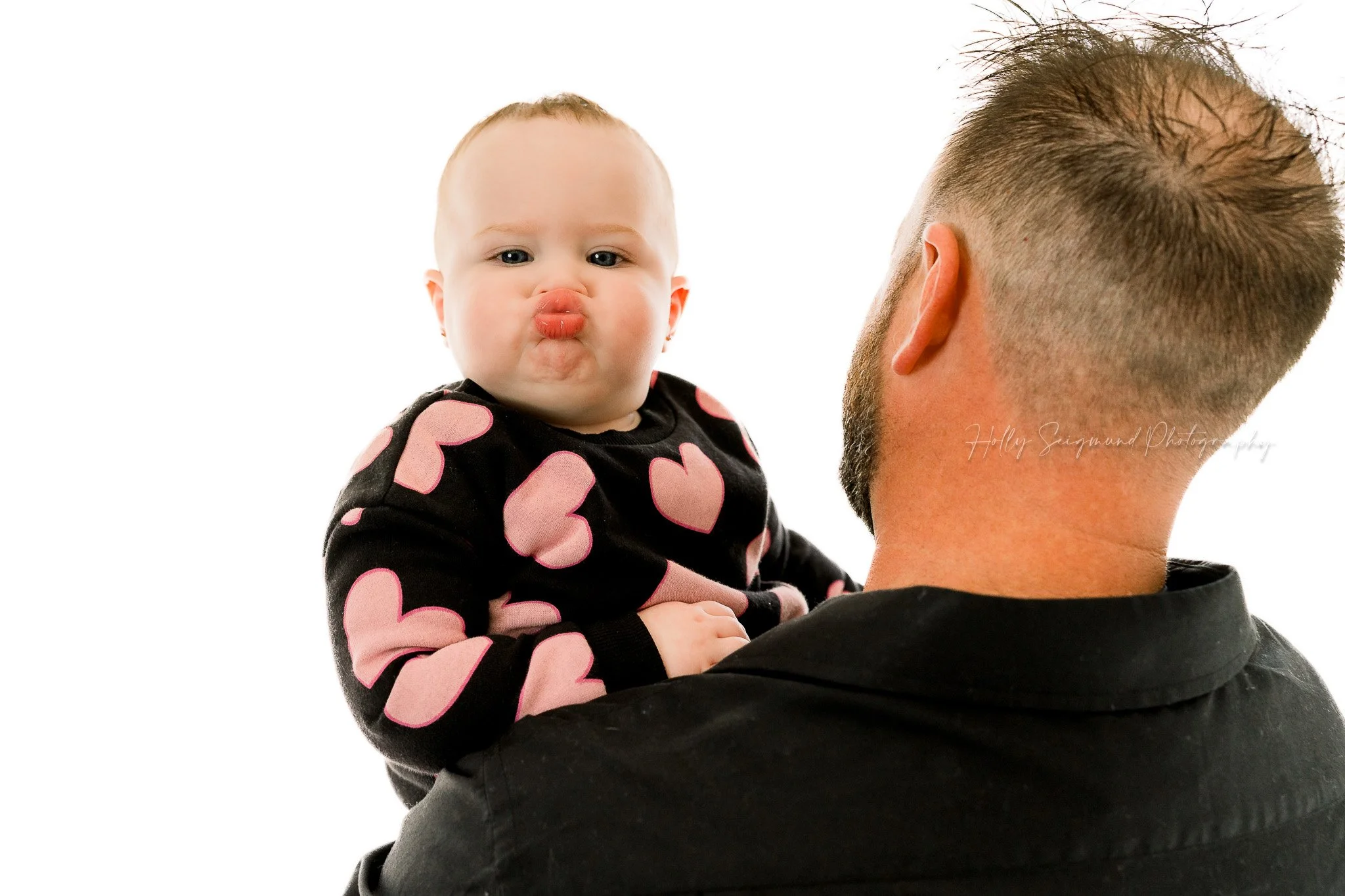 Baby girls kissy face during a birthday session in a studio in Lexington, Texas