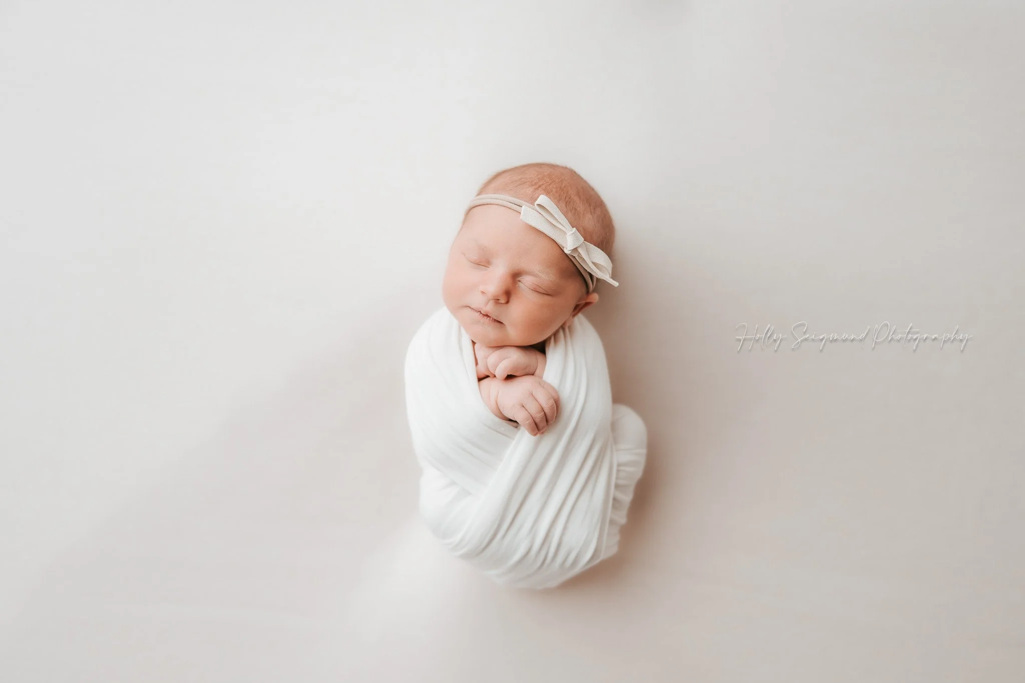 Newborn girl wrapped in white at a photography studio in Lexington, Texas