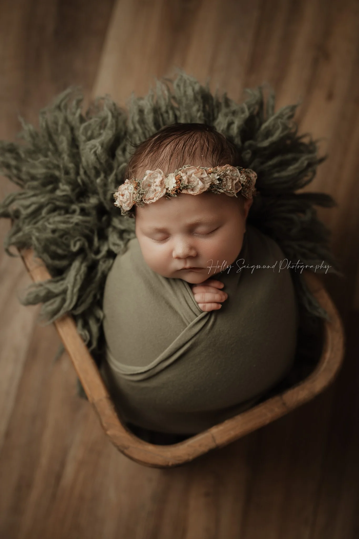 Newborn girl in a wooden basket with a floral crown in Central Texas newborn studio