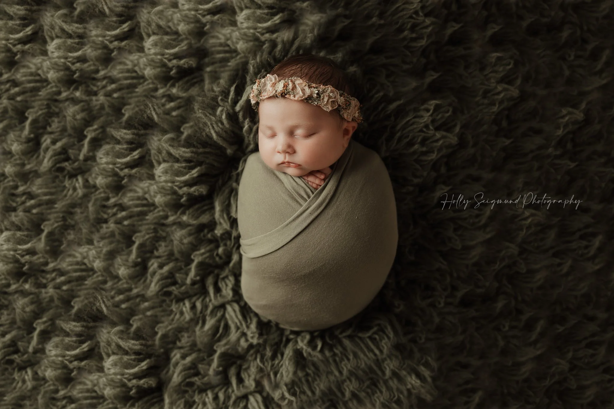Newborn baby girl laying on a Conifer Green Flokati in a Lee County studio